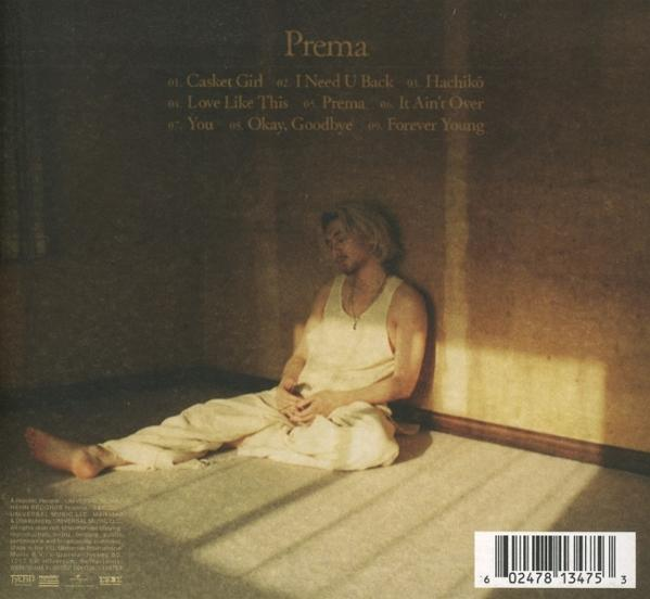 Ein Mann sitzt an einer Wand und trägt weiße Kleidung. Albumtitel 'Prema' steht oben. Titelliste ist sichtbar. Unten ist ein Barcode.