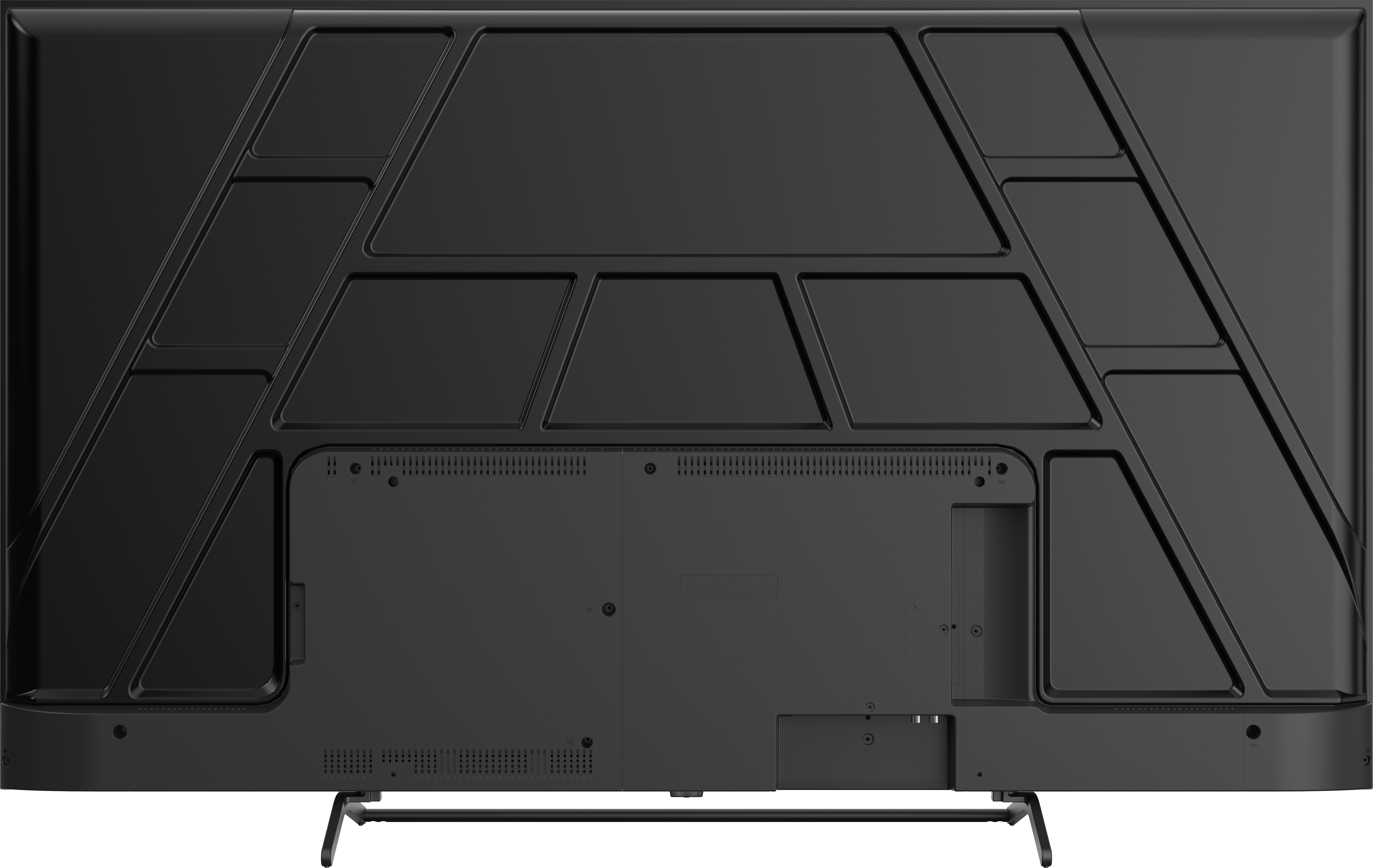 Tył czarnego telewizora. Prostokątny kształt z wieloma geometrycznymi elementami. Dwie nogi na dole. Widoczne porty i otwory wentylacyjne.