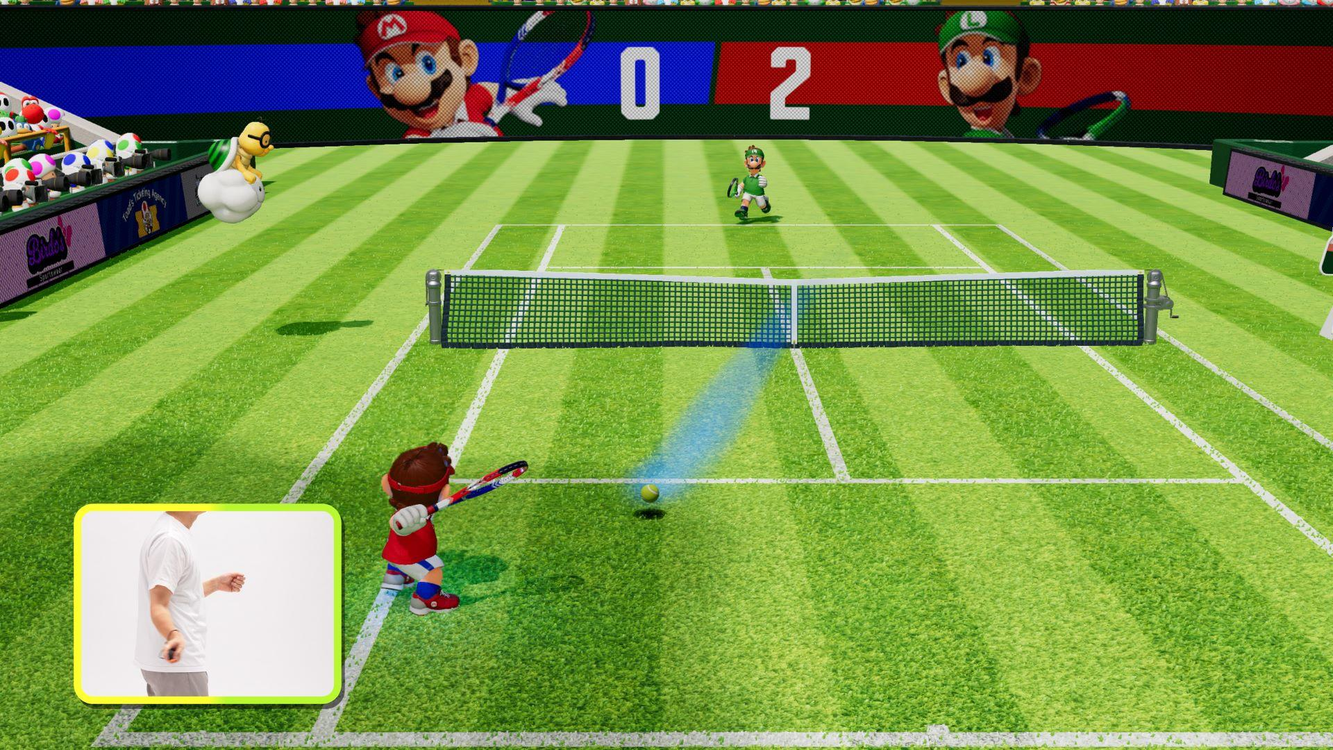 Mario-Tennis-Spiel. Mario schwingt seinen Schläger, Luigi rennt. Anzeigetafel zeigt 0:2. Grüner Platz, blauer und roter Hintergrund.