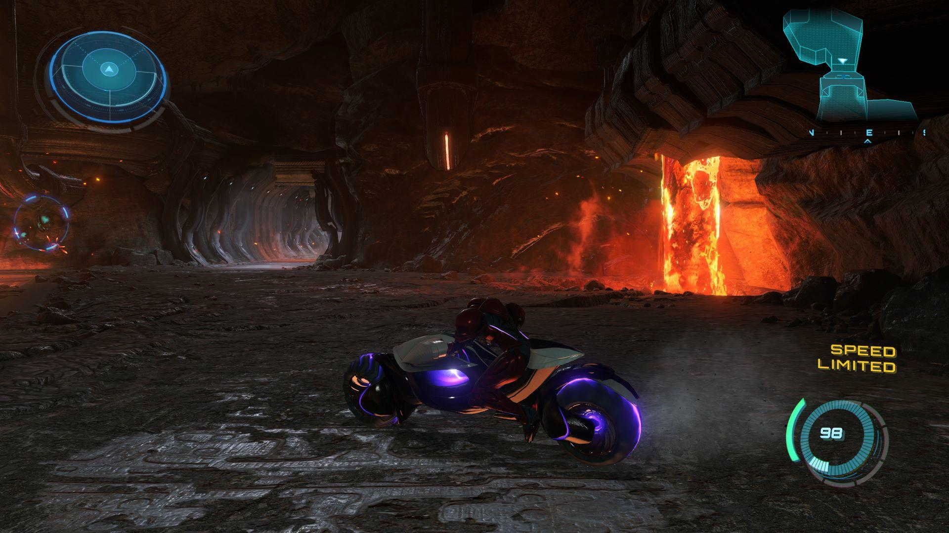 Ein futuristisches Motorrad fährt durch eine dunkle Höhle. Lava leuchtet im Hintergrund. Geschwindigkeitsbegrenzung und andere UI-Elemente sind sichtbar.