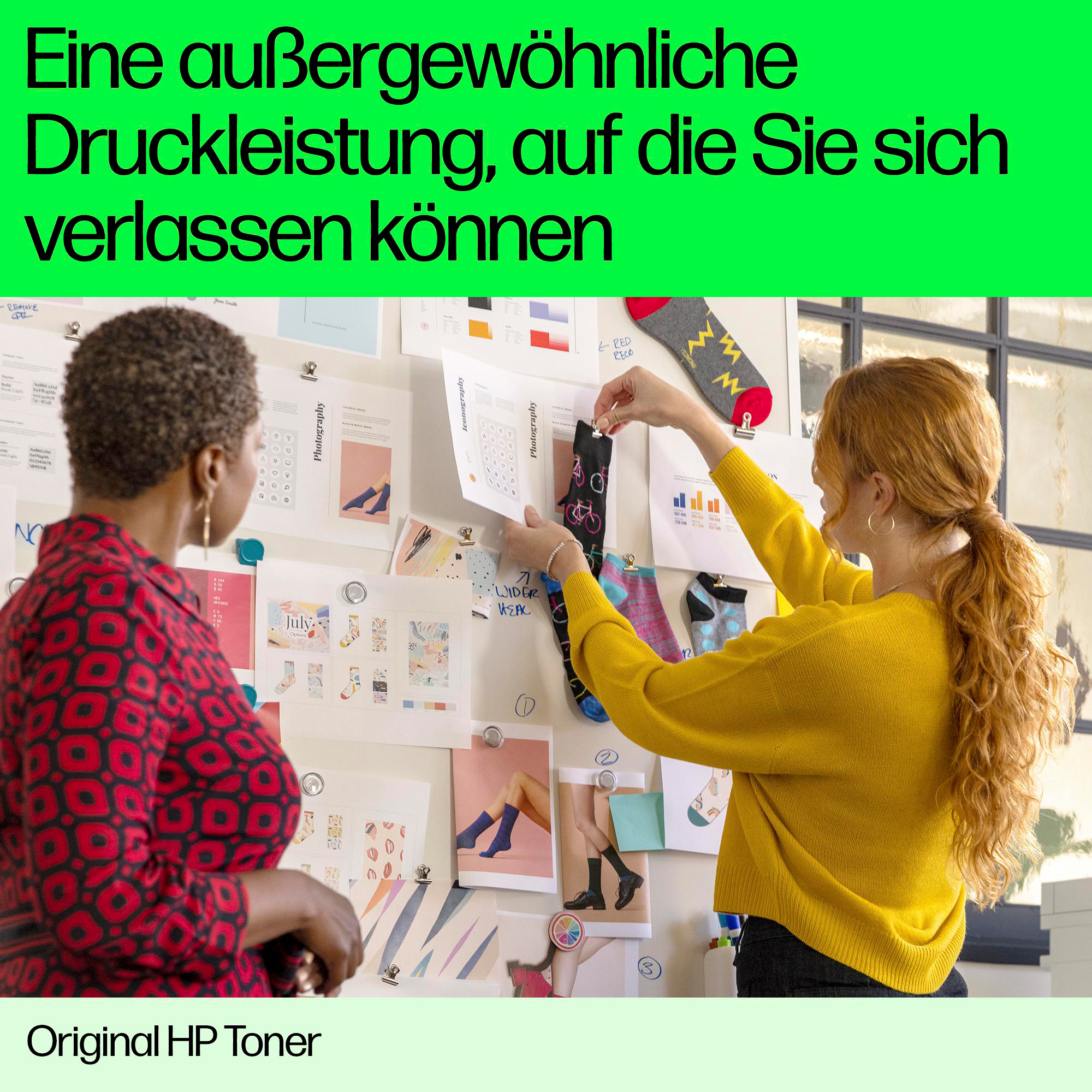 Zwei Frauen betrachten ein Moodboard mit Socken. Eine in rotem Oberteil, die andere in gelbem Pullover. Text: „außergewöhnliche Druckleistung“.