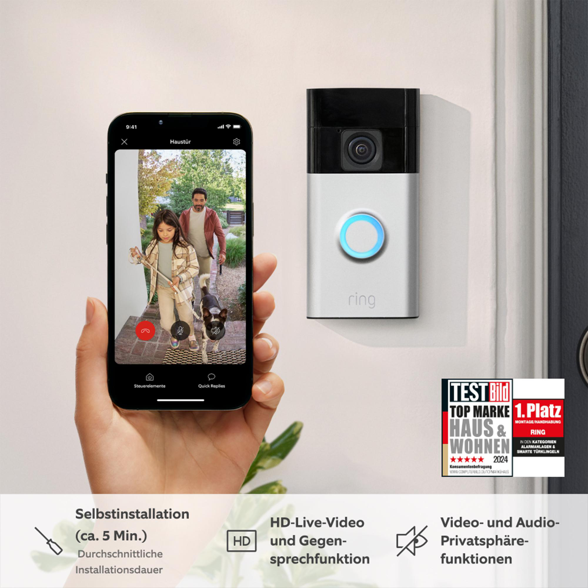 Eine Person, die ein Telefon hält, das ein Video eines Mädchens, eines Mannes und eines Hundes zeigt. Eine Ring-Türklingel ist an der Wand.