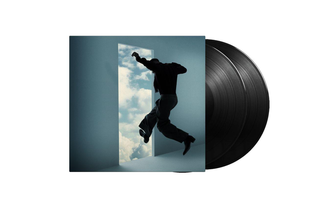 Ein Vinyl-Albumcover. Eine Person springt durch eine Tür in einen bewölkten Himmel. Das Album ist neben zwei schwarzen Schallplatten.
