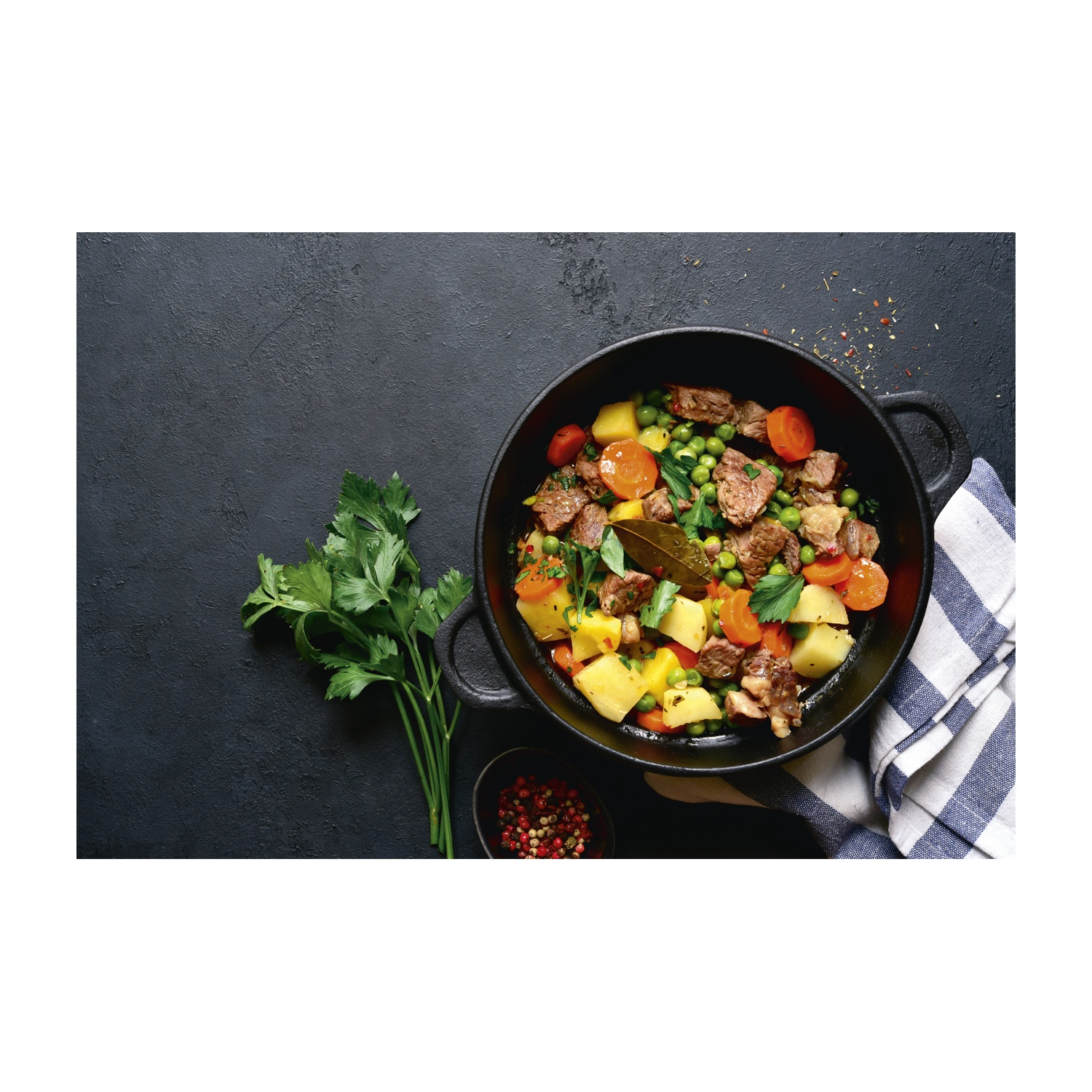 Stufato in pentola nera, con patate, carote, piselli e carne. Prezzemolo e spezie su sfondo scuro.