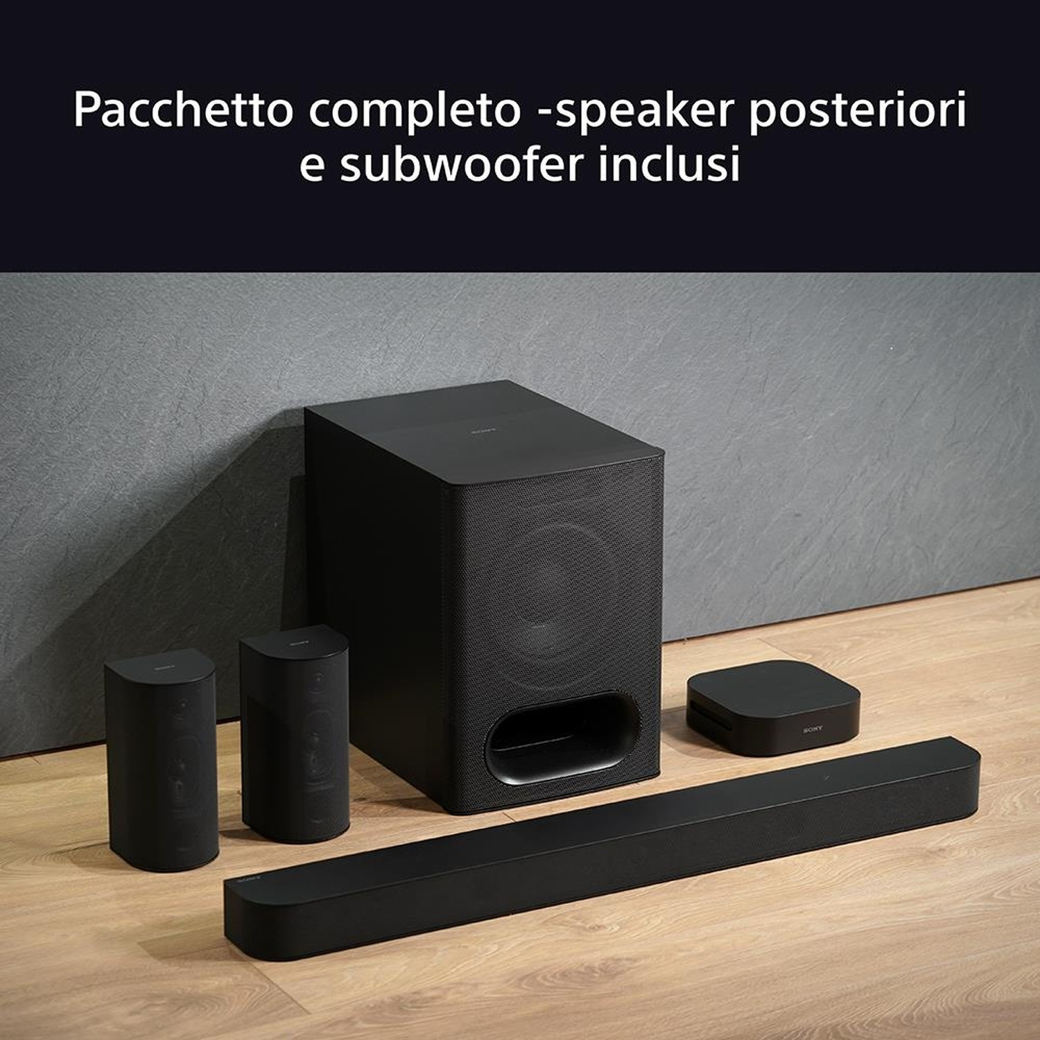 Set di sistemi audio neri su pavimento in legno. Include un subwoofer, una soundbar, due piccoli altoparlanti e un piccolo dispositivo quadrato.