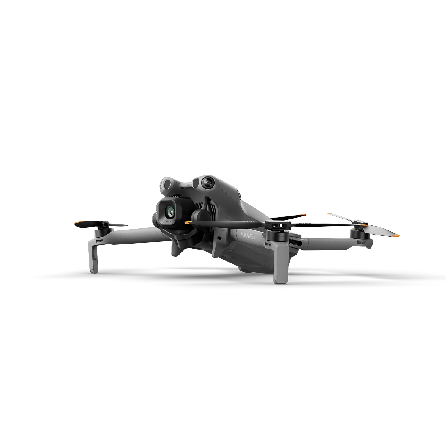 Un dron gris con cuatro hélices, una cámara y detalles naranjas, proyectando una sombra sobre un fondo gris.