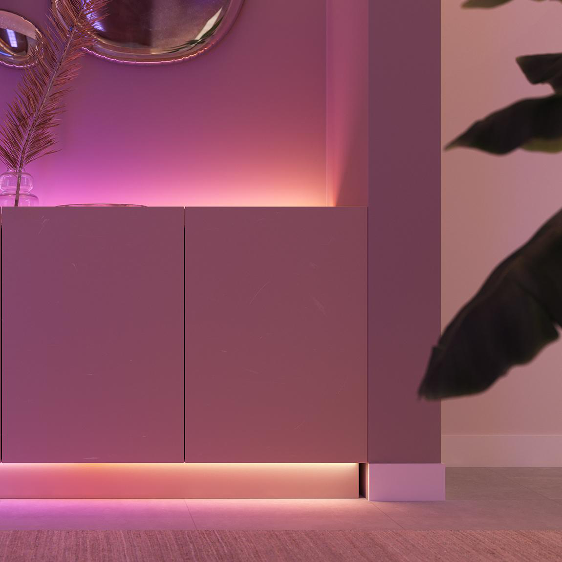 Ein modernes Interieur mit lilafarbenen Schränken, beleuchtet von rosa Lichtern. Ein Spiegel und eine Pflanze ergänzen das Dekor.