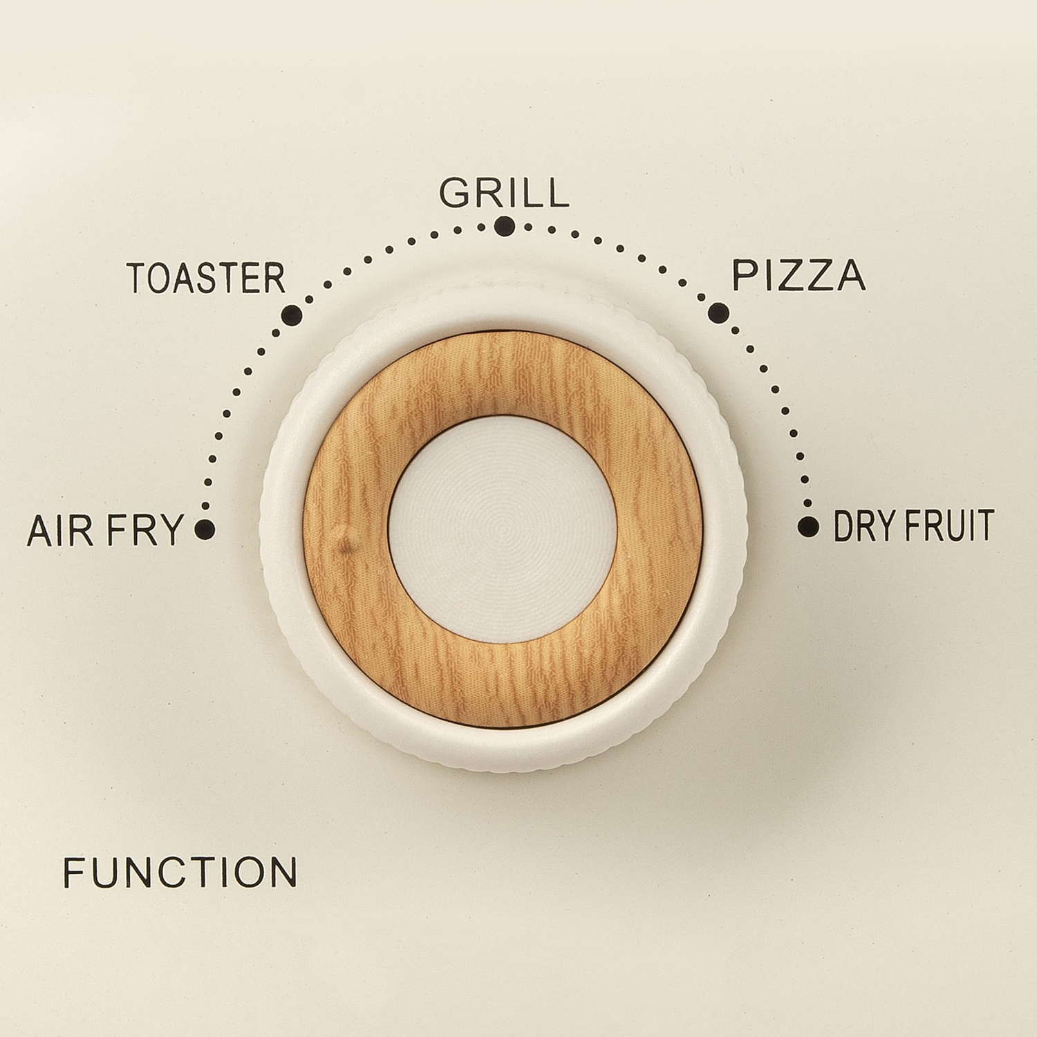 Primo piano di un quadrante delle funzioni con impostazioni: Air Fry, Tostapane, Grill, Pizza, Frutta secca. Quadrante bianco con centro in legno, su superficie beige.