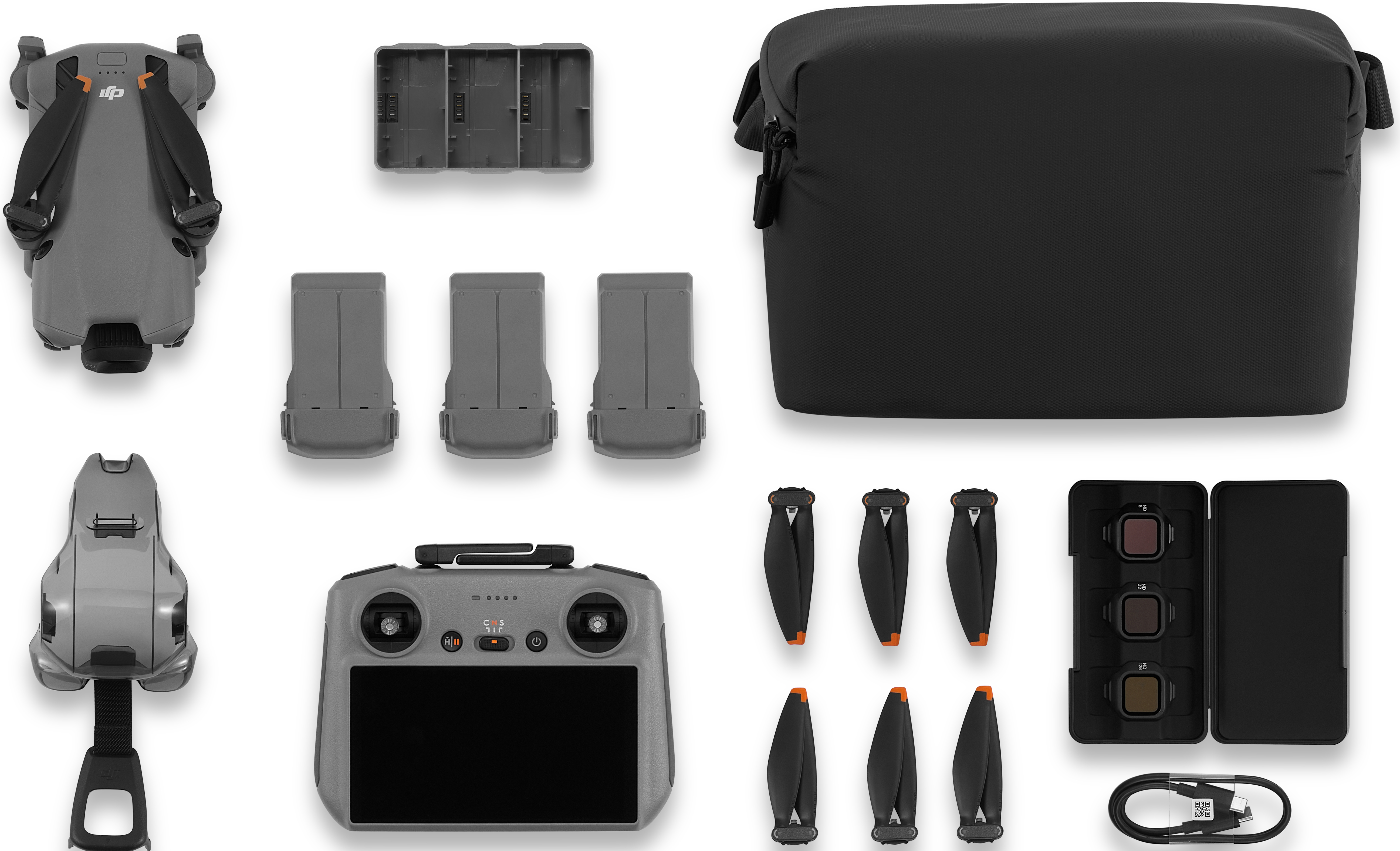 Kit drone: drone grigio, controller, batterie, caricabatterie, eliche, filtri e custodia. Tutto ordinatamente disposto su superficie bianca.