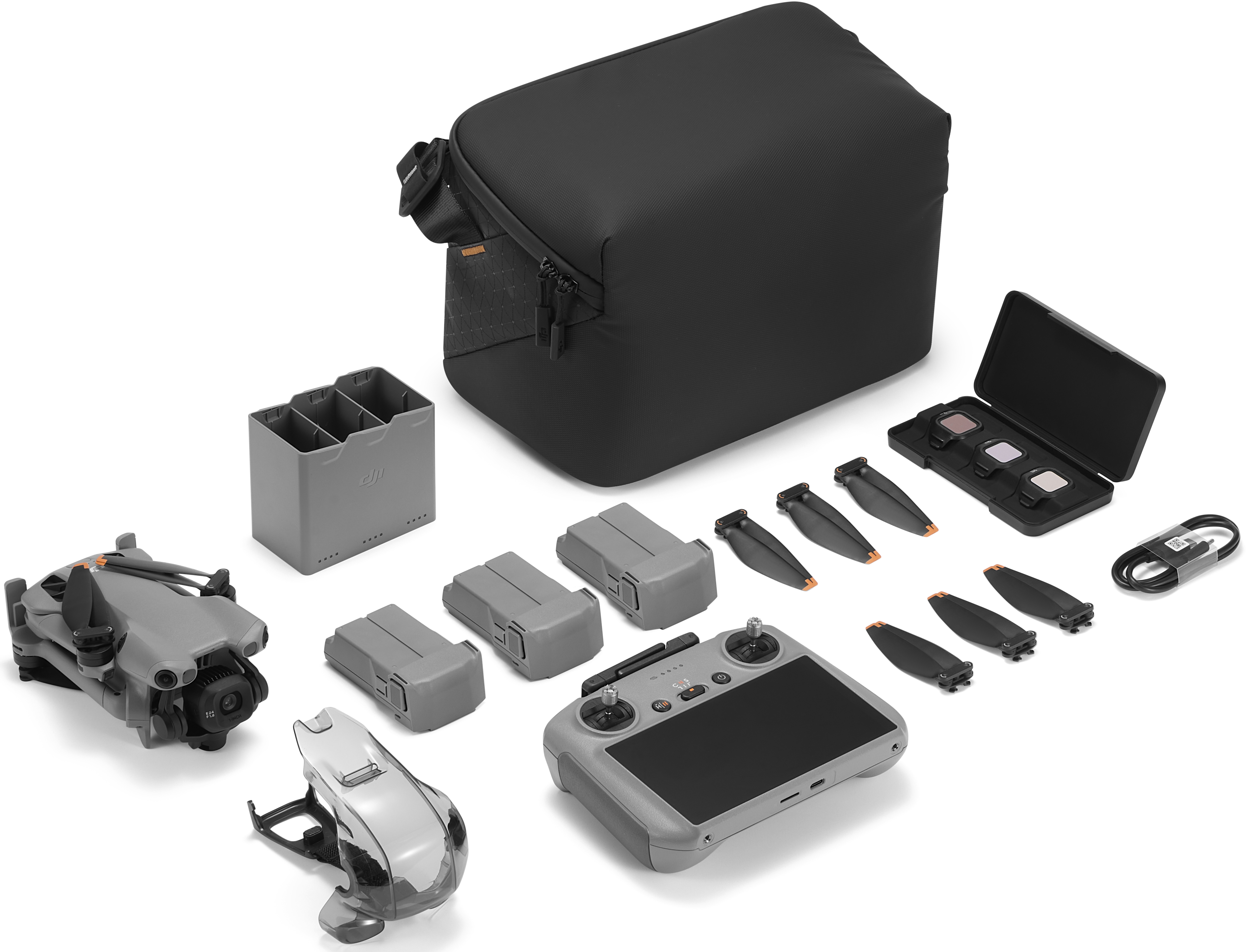 Un kit drone con drone, controller, batterie, borsa, eliche, filtri e cavo di ricarica, tutto su sfondo bianco.