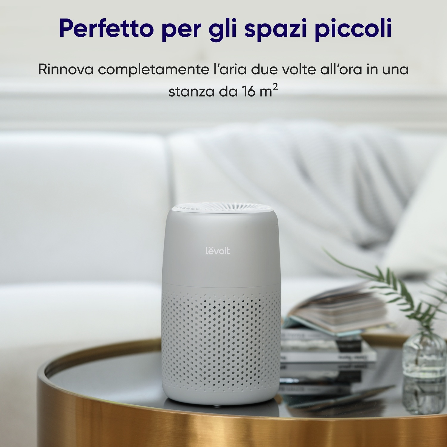 Un purificatore d'aria bianco su un tavolo rotondo. Il testo sopra dice: 'Perfetto per piccoli spazi'. Un divano sullo sfondo.