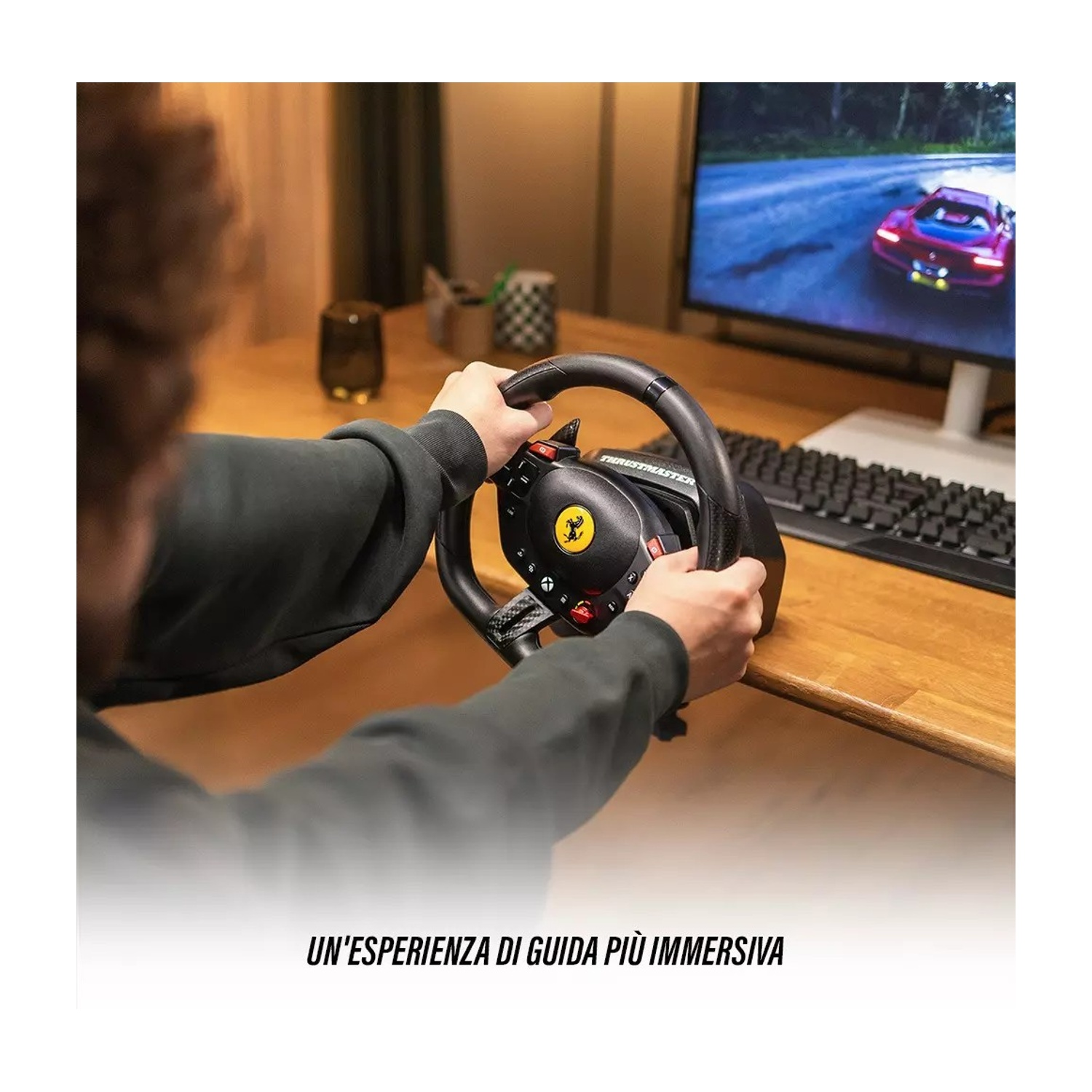 Una persona tiene un volante Ferrari, con un monitor di computer che mostra un'auto da corsa. La scena è ambientata su una scrivania di legno.