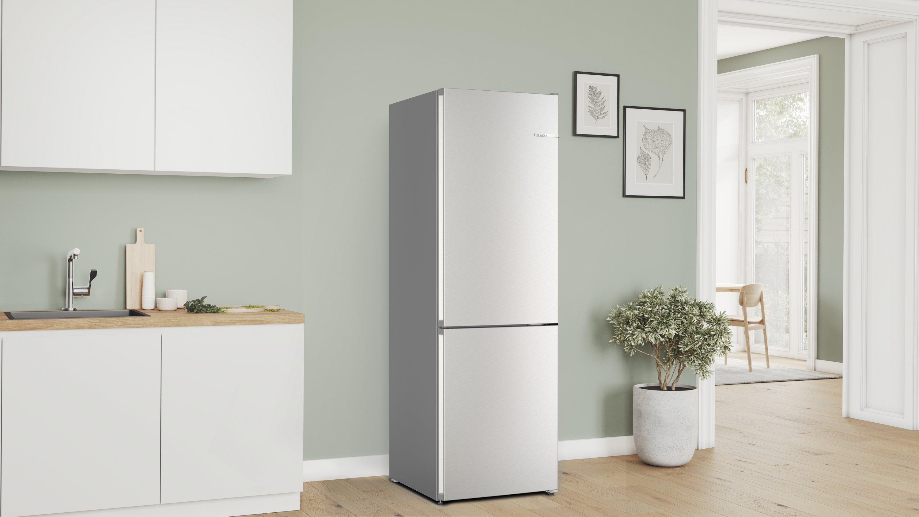 Eine moderne Küche mit Kühlschrank, Schränken und einer Pflanze. Die Wände sind hellgrün, der Boden ist aus Holz.