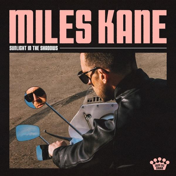 Album borító Miles Kane-nel, napszemüvegben, motoron. A 'Miles Kane' és a 'Sunlight in the Shadows' címek láthatók.