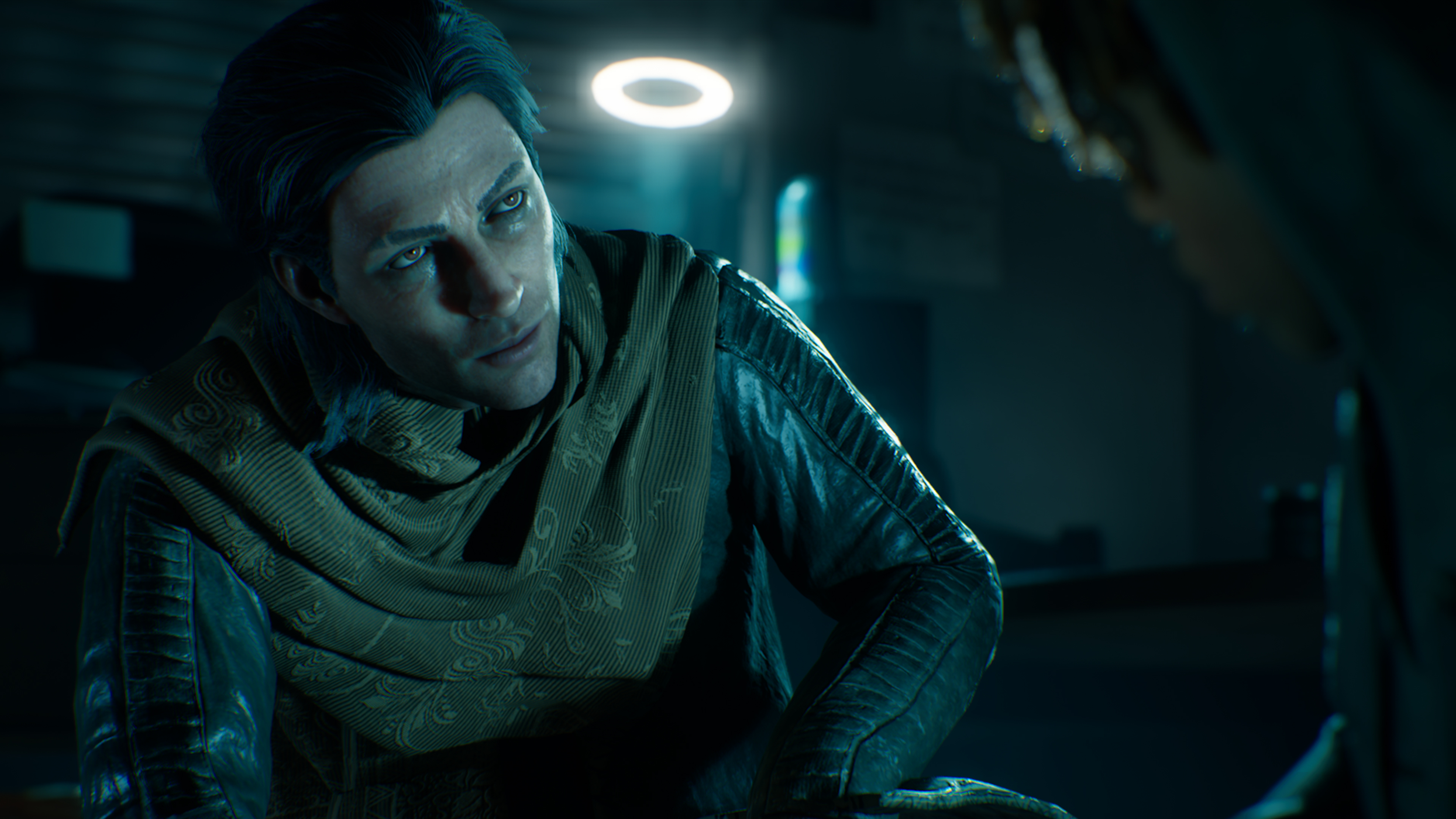 Mężczyzna z ciemnymi włosami patrzy w górę. Ma na sobie zielony szalik i czarną skórzaną kurtkę. Nad nim świeci jasne światło pierścieniowe.