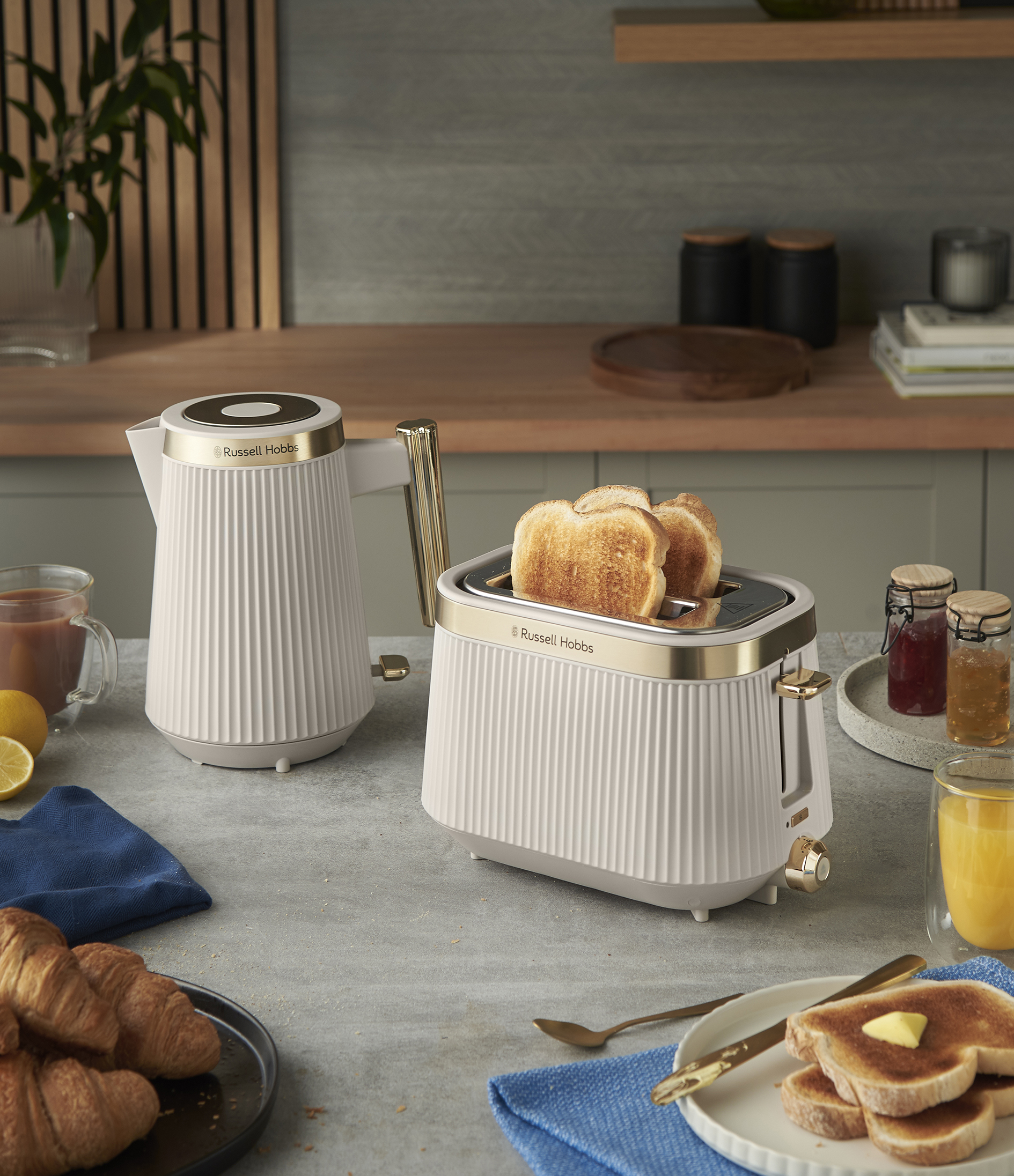 Reggeli jelenet kenyérpirítóval, vízforralóval és vajjal megkent pirítóssal. A croissant, a juice és a lekvár teszi teljessé.