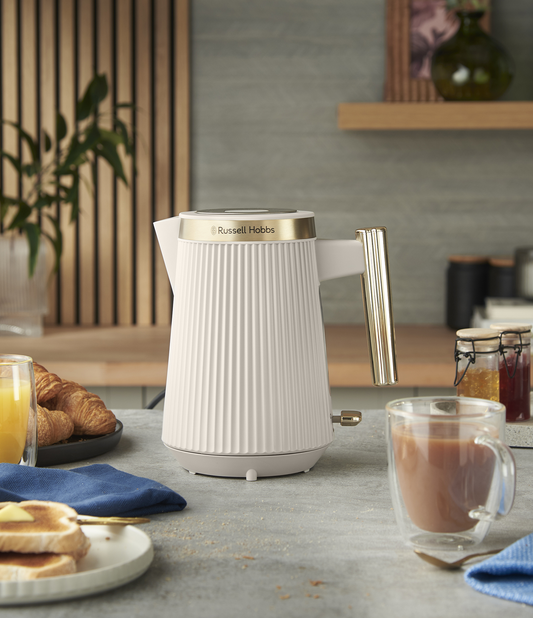 Fehér Russell Hobbs vízforraló arany díszítéssel. Reggeli beállítás pirítóssal, croissant-nal és teával.