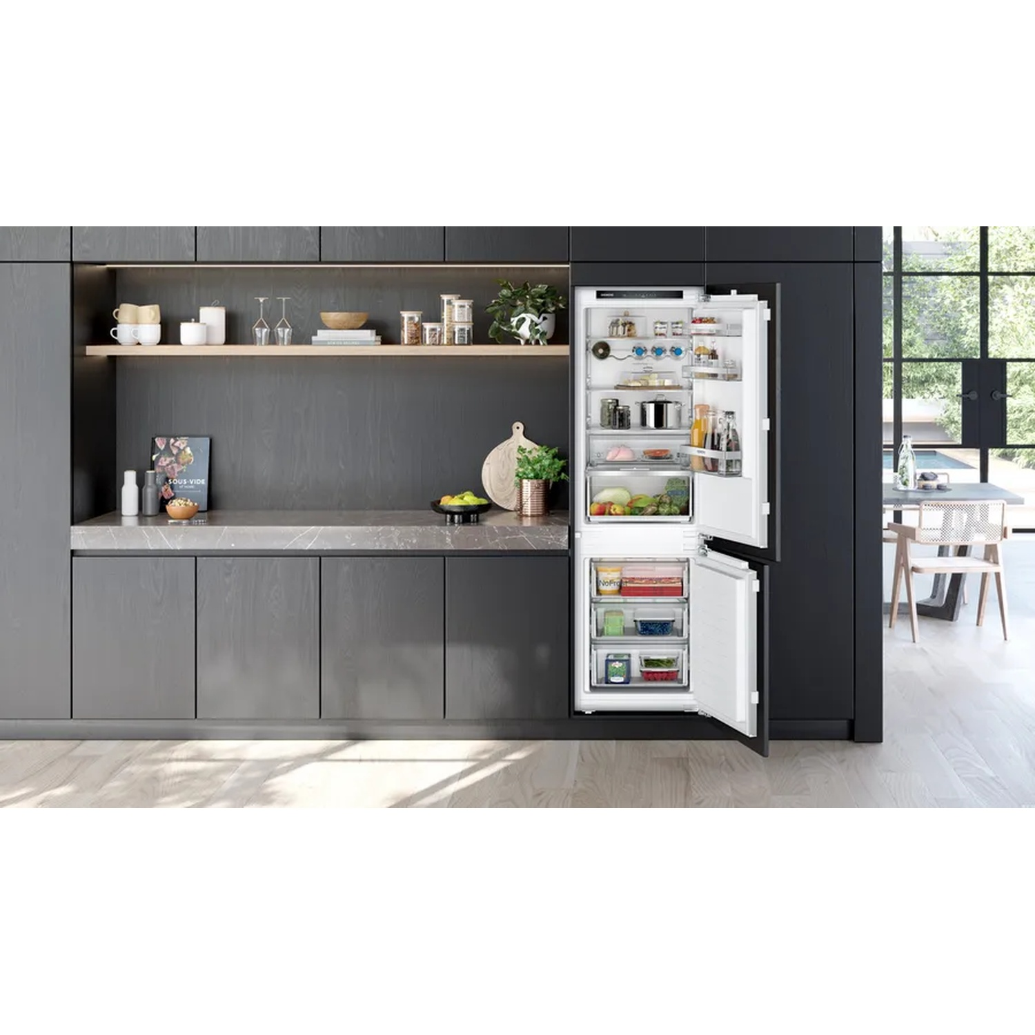 Een moderne keuken met een open koelkast. Binnenin zijn planken vol voedsel. Kasten en planken zijn donkergrijs.