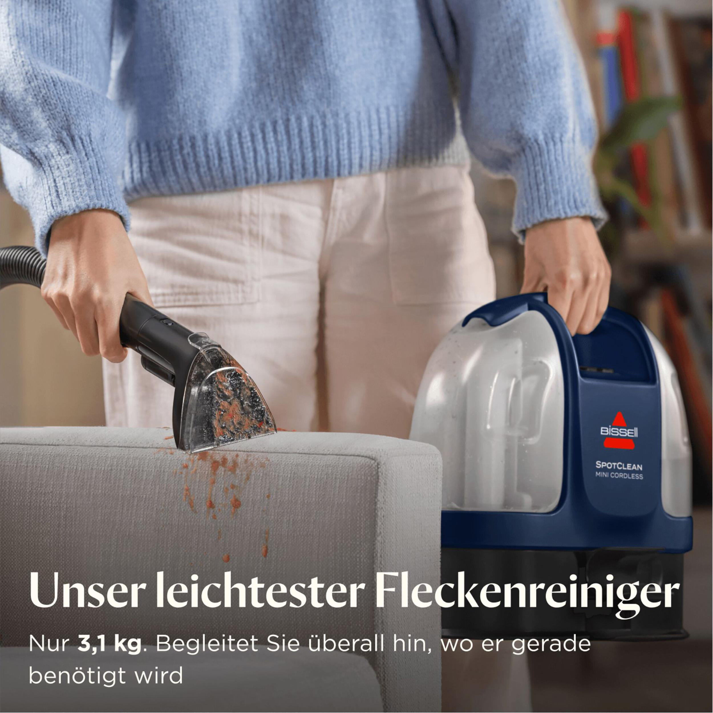 Eine Person reinigt eine Couch mit einem Bissell SpotClean. Maschine und Couch sind sichtbar. Der Text besagt, dass es sich um einen leichten Fleckenentferner handelt.