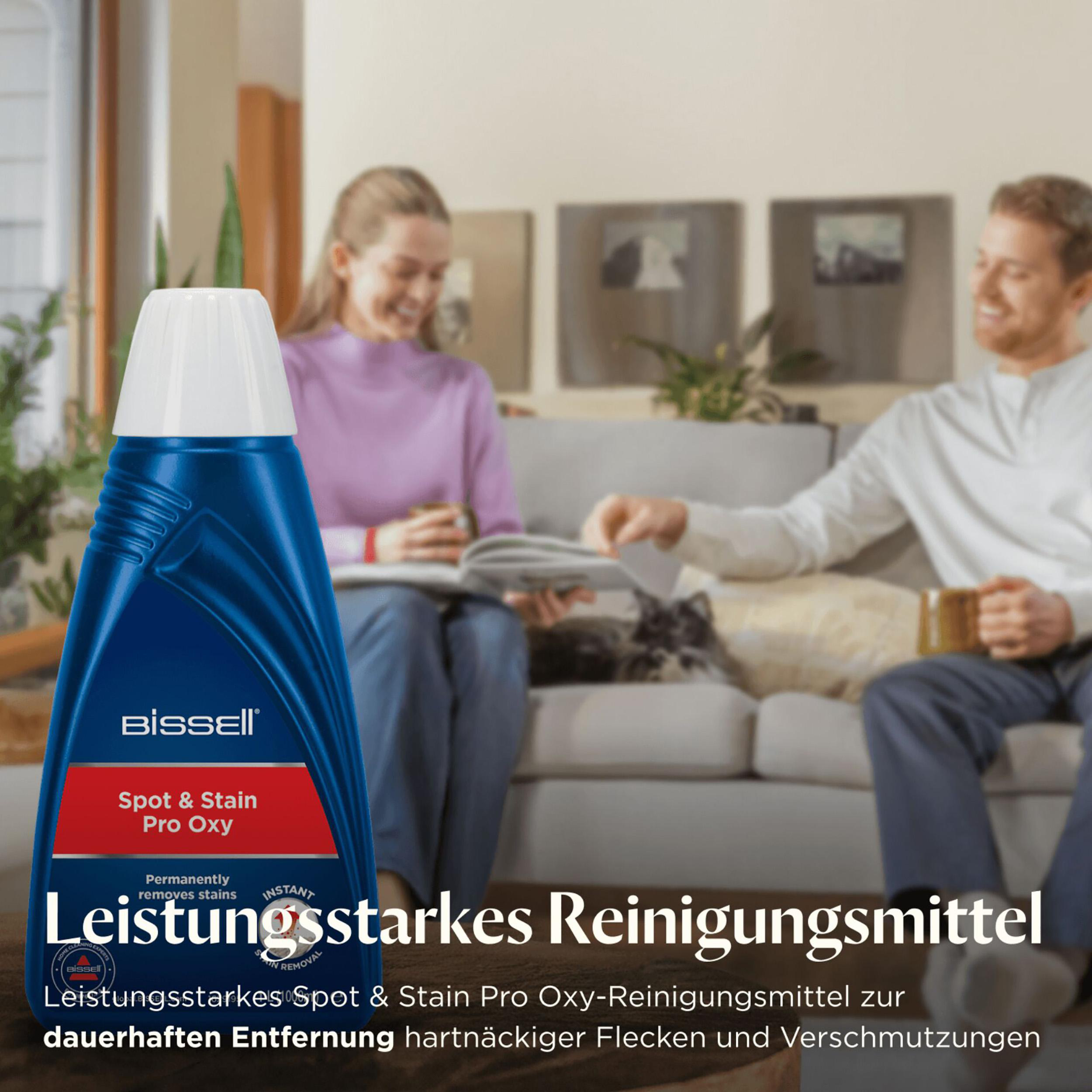 Eine Reinigungsflasche steht vor einem Paar auf einem Sofa. Das Produkt ist Spot & Stain Pro Oxy.