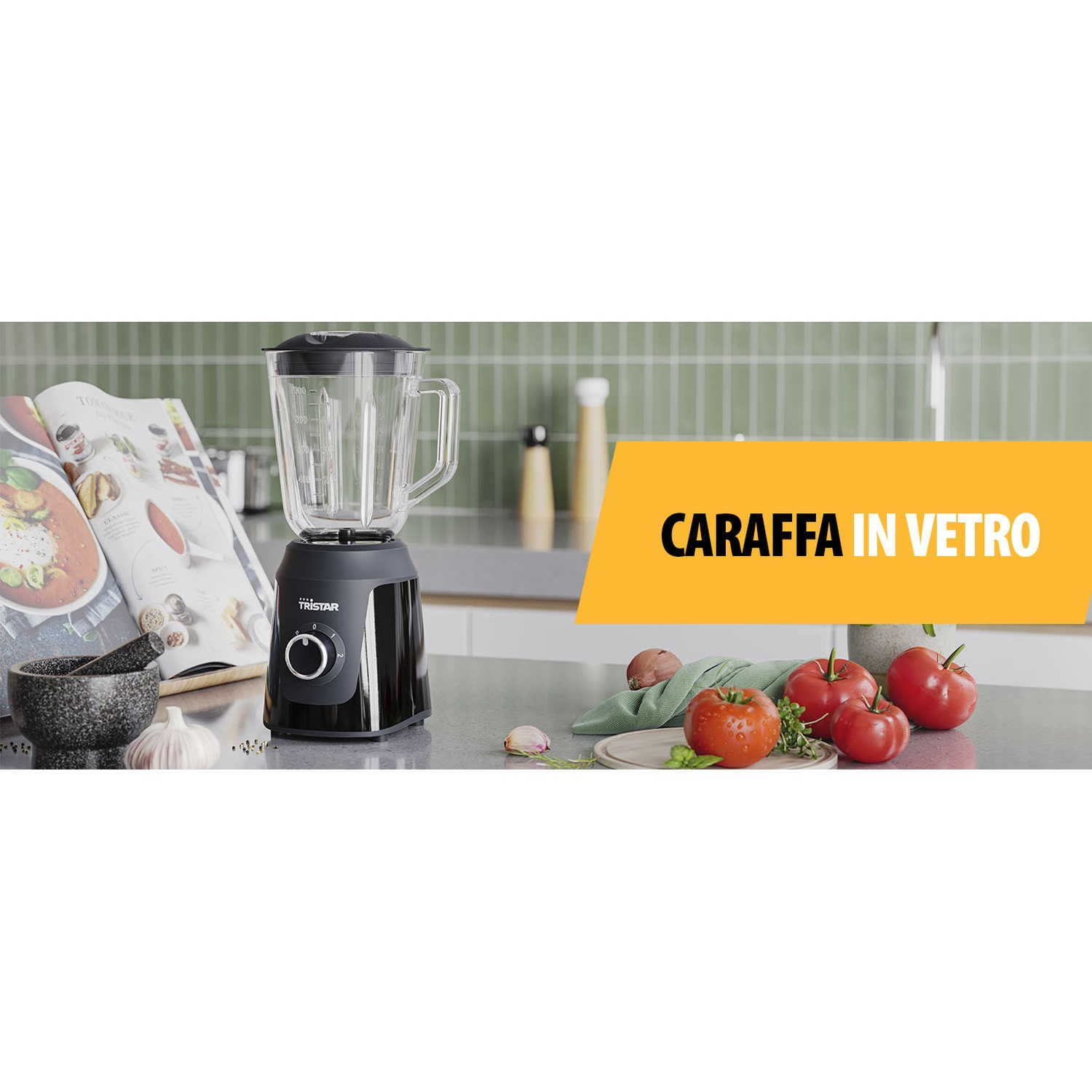 Un frullatore con una caraffa di vetro è su un bancone. Sono presenti anche pomodori, aglio e un libro di cucina. Il testo dice 'CARAFFA IN VETRO'.