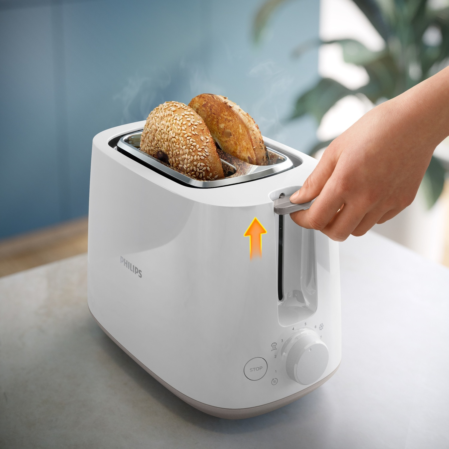 Tostapane Philips bianco con bagel tostati. Una mano alza la leva. Una freccia arancione indica il movimento verso l'alto.