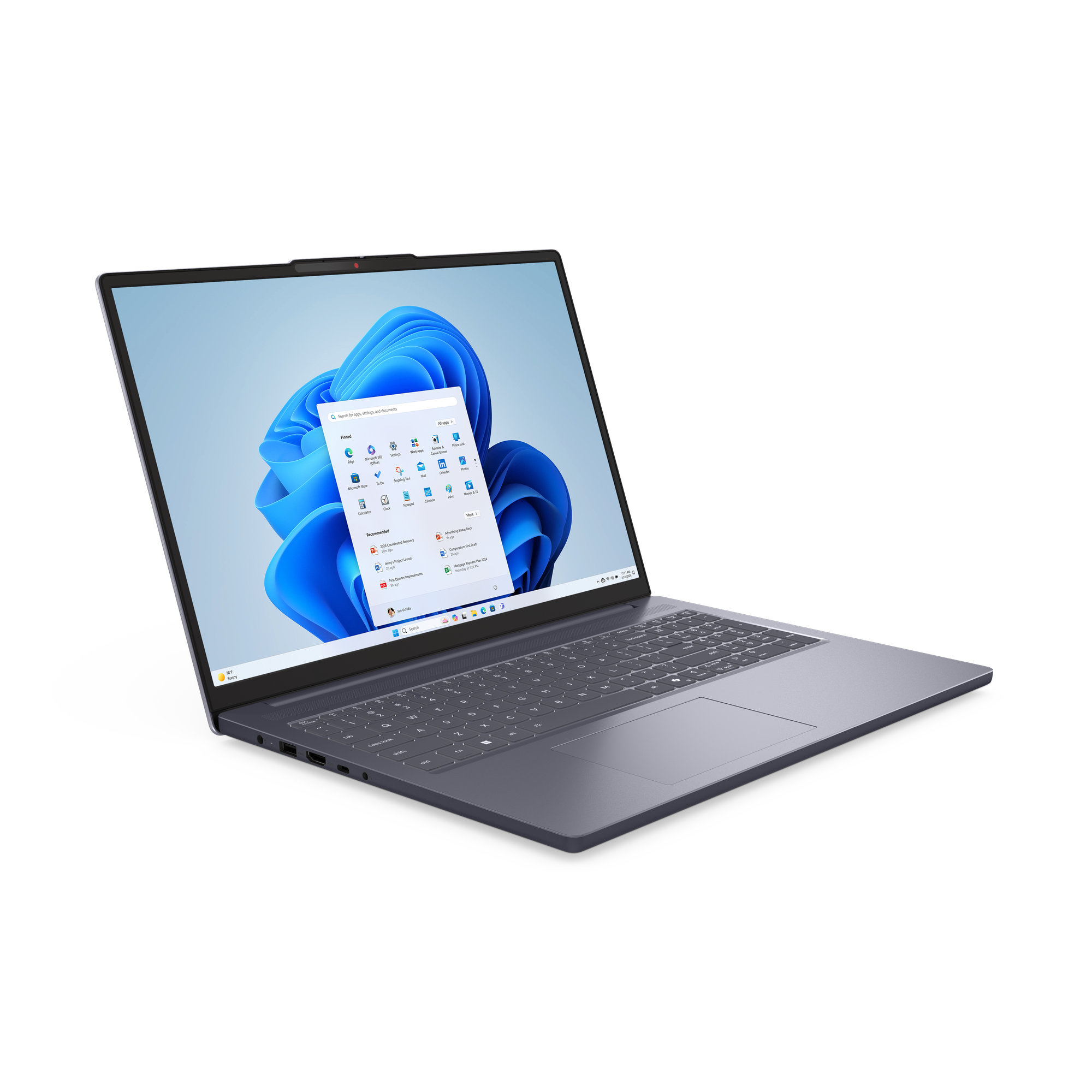Un ordinateur portable gris affiche l'interface Windows 11 avec des icônes et un fond bleu. Il est ouvert sur une surface noire.