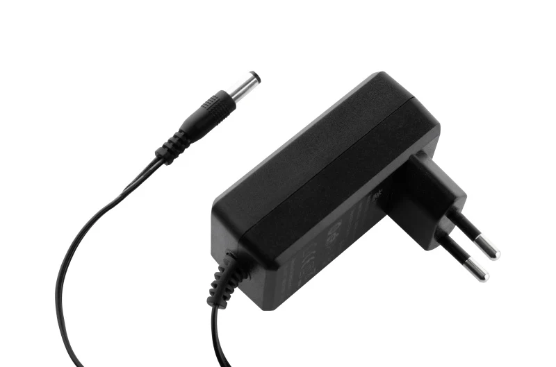 Egy fekete hálózati adapter dugóval és DC csatlakozóval. A kábel és a csatlakozó fekete.