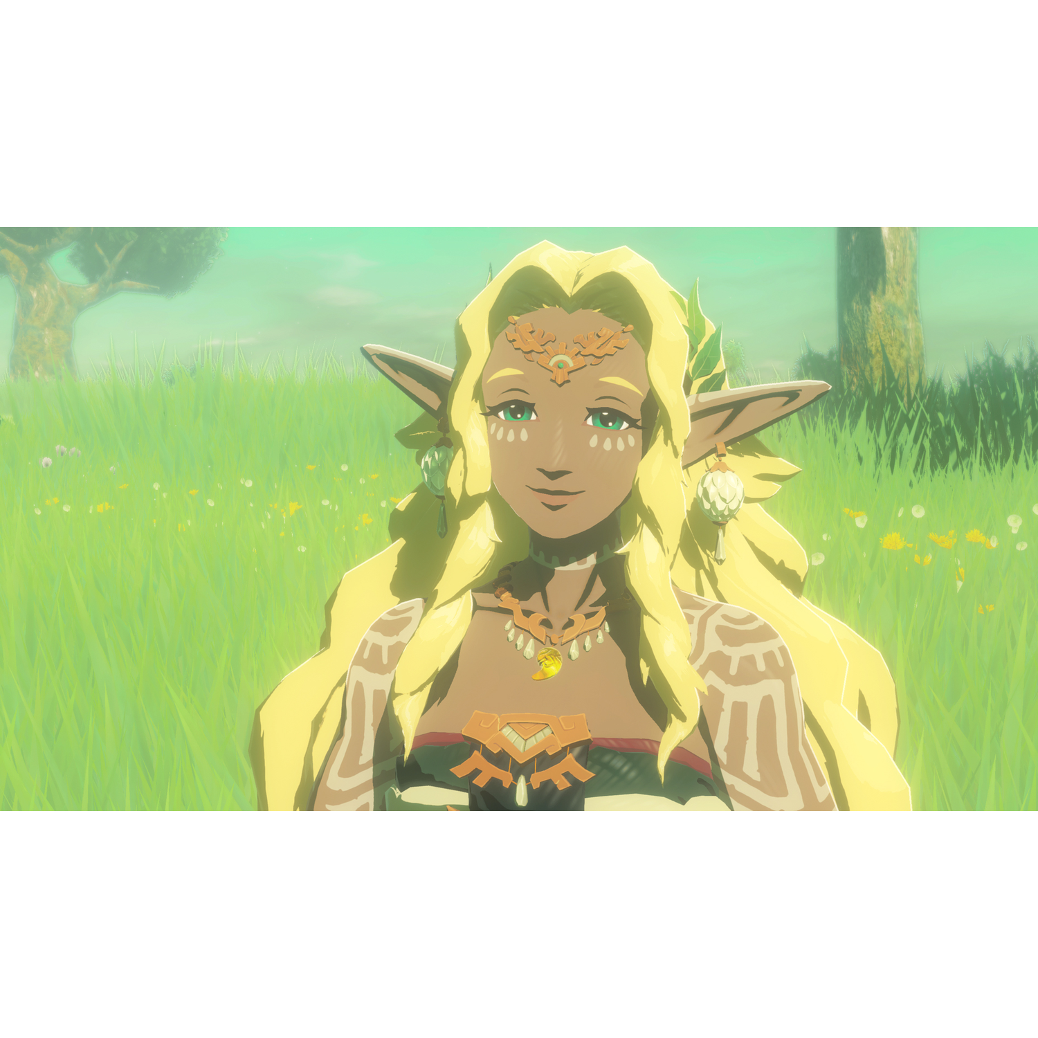 Een vrouw met blond haar en groene ogen staat in een grasveld. Ze draagt sieraden en heeft markeringen op haar armen. Bomen op de achtergrond.
