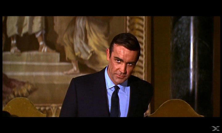 Sean Connery im Anzug, blickt in die Kamera. Im Hintergrund ein Gemälde. Rechts eine Säule.
