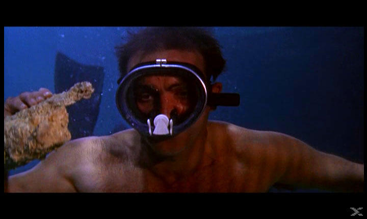 Mann mit Tauchmaske unter Wasser hält eine Flasche. Blauer Wasserhintergrund. Das Gesicht des Mannes ist sichtbar, und er ist ohne Hemd.