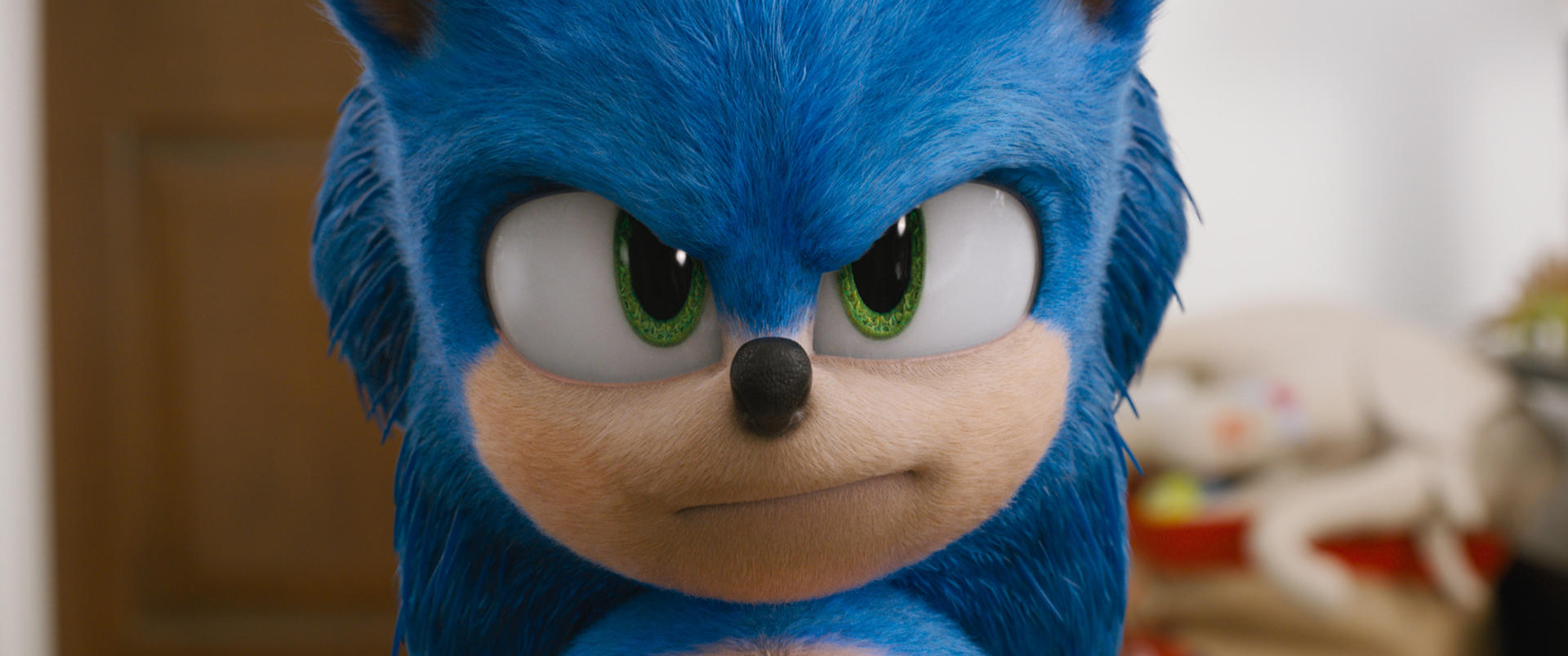 Nahaufnahme von Sonic the Hedgehogs Gesicht. Er hat blaues Fell, grüne Augen und eine schwarze Nase. Der Hintergrund ist unscharf.