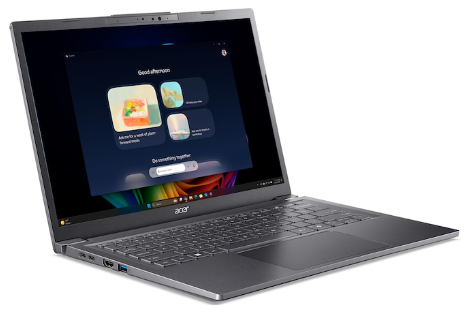 Un portátil Acer gris muestra una pantalla azul oscuro con iconos de aplicaciones. La pantalla muestra un menú con opciones como 'Buenas tardes'.