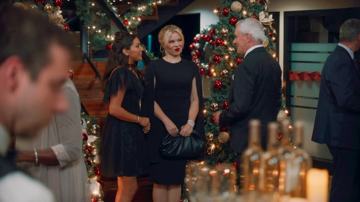 Leute auf einer Weihnachtsfeier. Frauen in schwarzen Kleidern, Männer in Anzügen, Weihnachtsbaum, Weinflaschen und Treppen sind sichtbar.