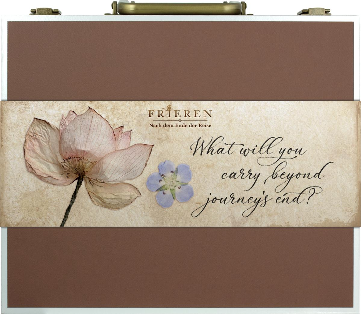 Brauner und silberner Aktenkoffer mit floralem Design und den Worten 'Was werden Sie am Ende der Reise mitnehmen?'