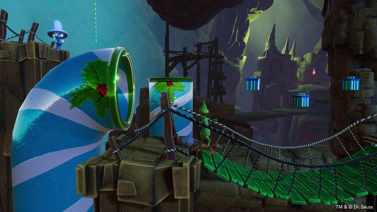 Der Grinch überquert eine Brücke in einer skurrilen Szene mit blau-weiß gestreiften Röhren, Geschenken und einer blauen Figur.