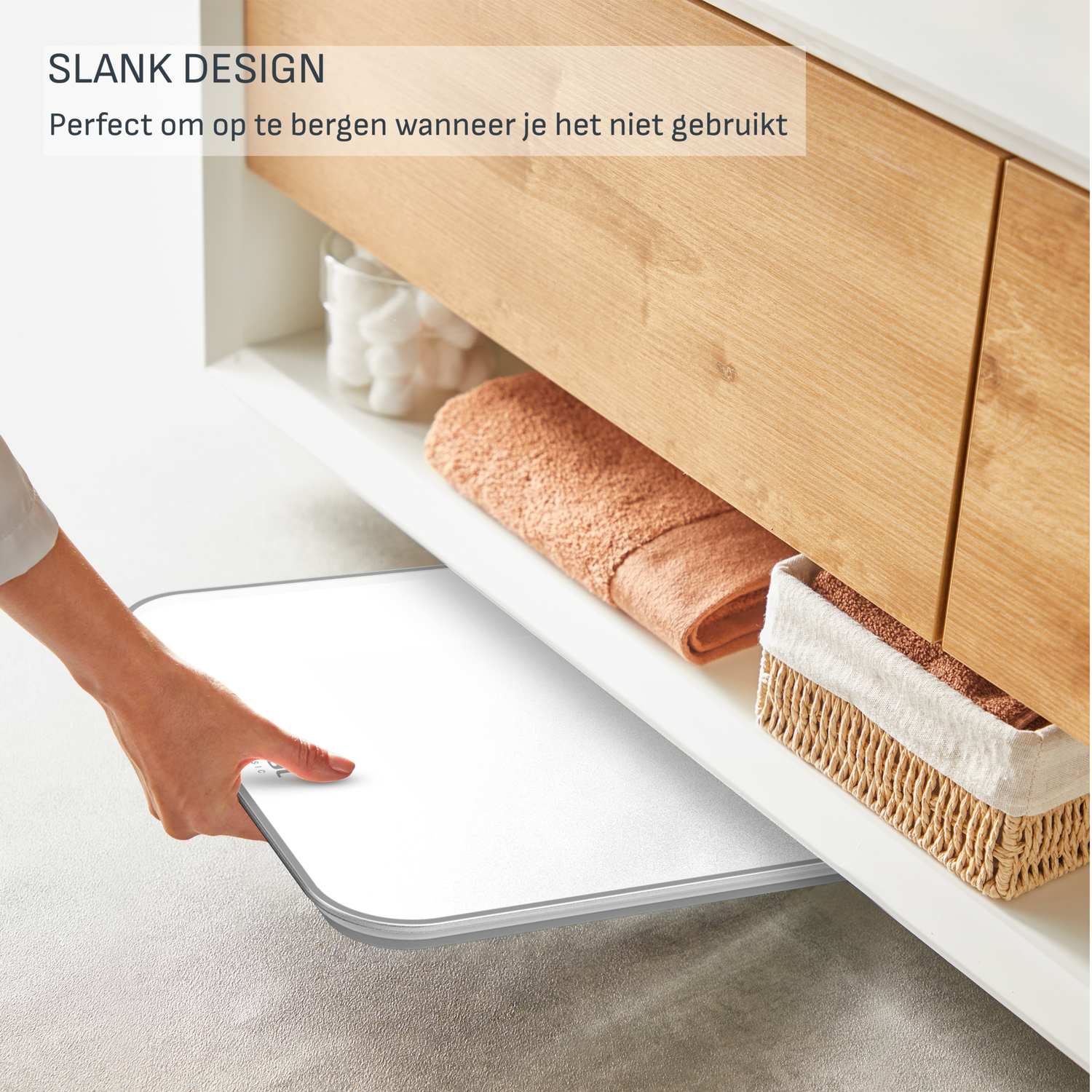 A person slides a white tray out from under a cabinet. There's a towel, basket, and cotton balls inside the cabinet.