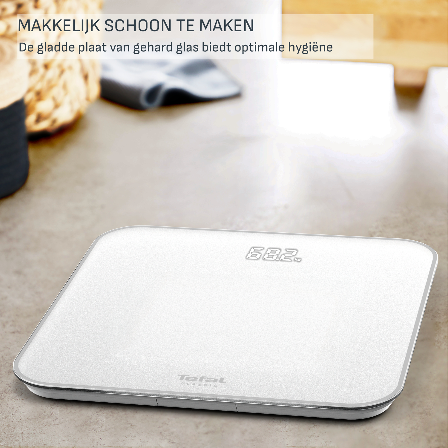 A white Tefal scale displays 68.2 kg. It sits on a light brown surface with text above. The scale has a silver trim.