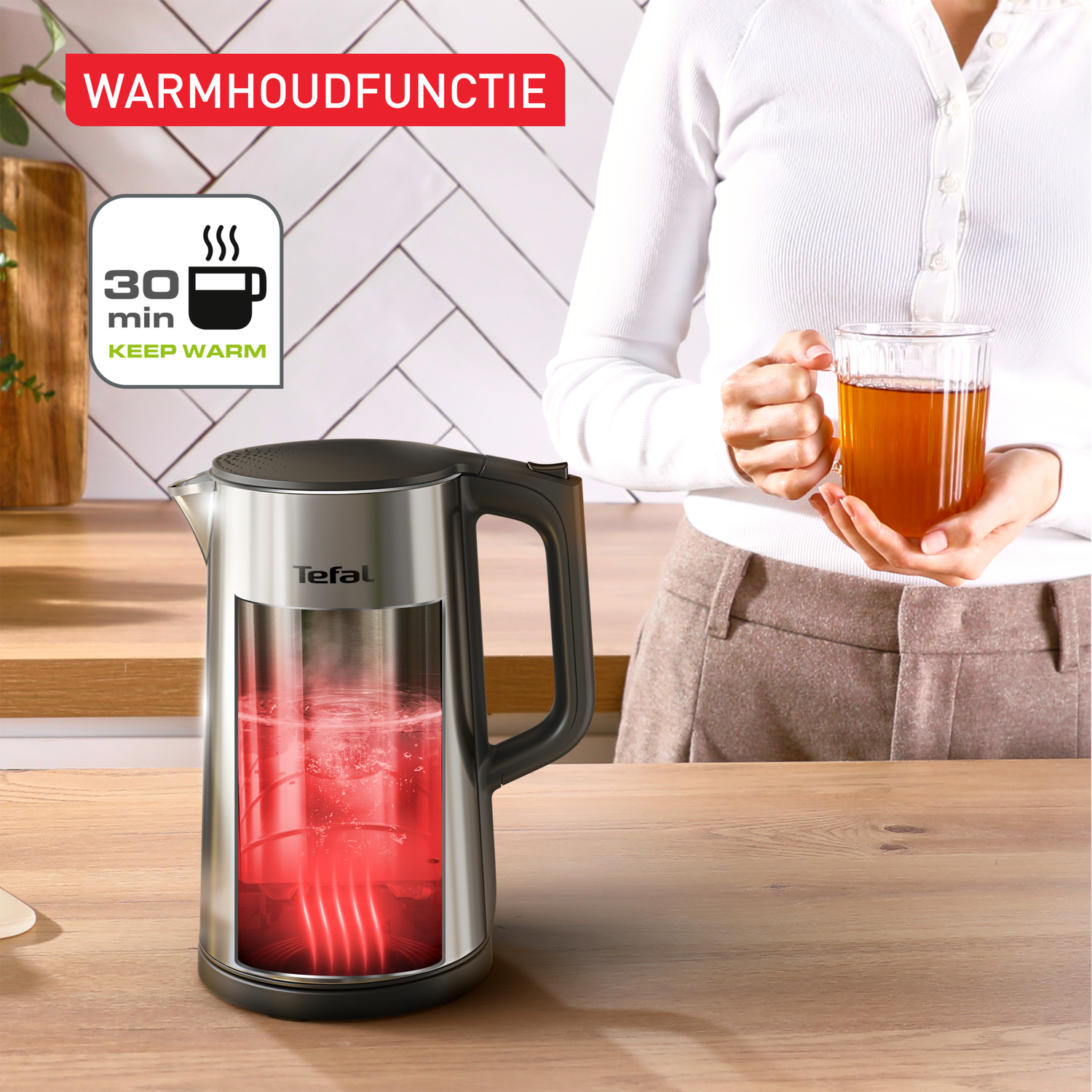 A person holding a tea cup. A kettle with water inside is on the table. Text on the top says 'Warmhoudfunctie'.