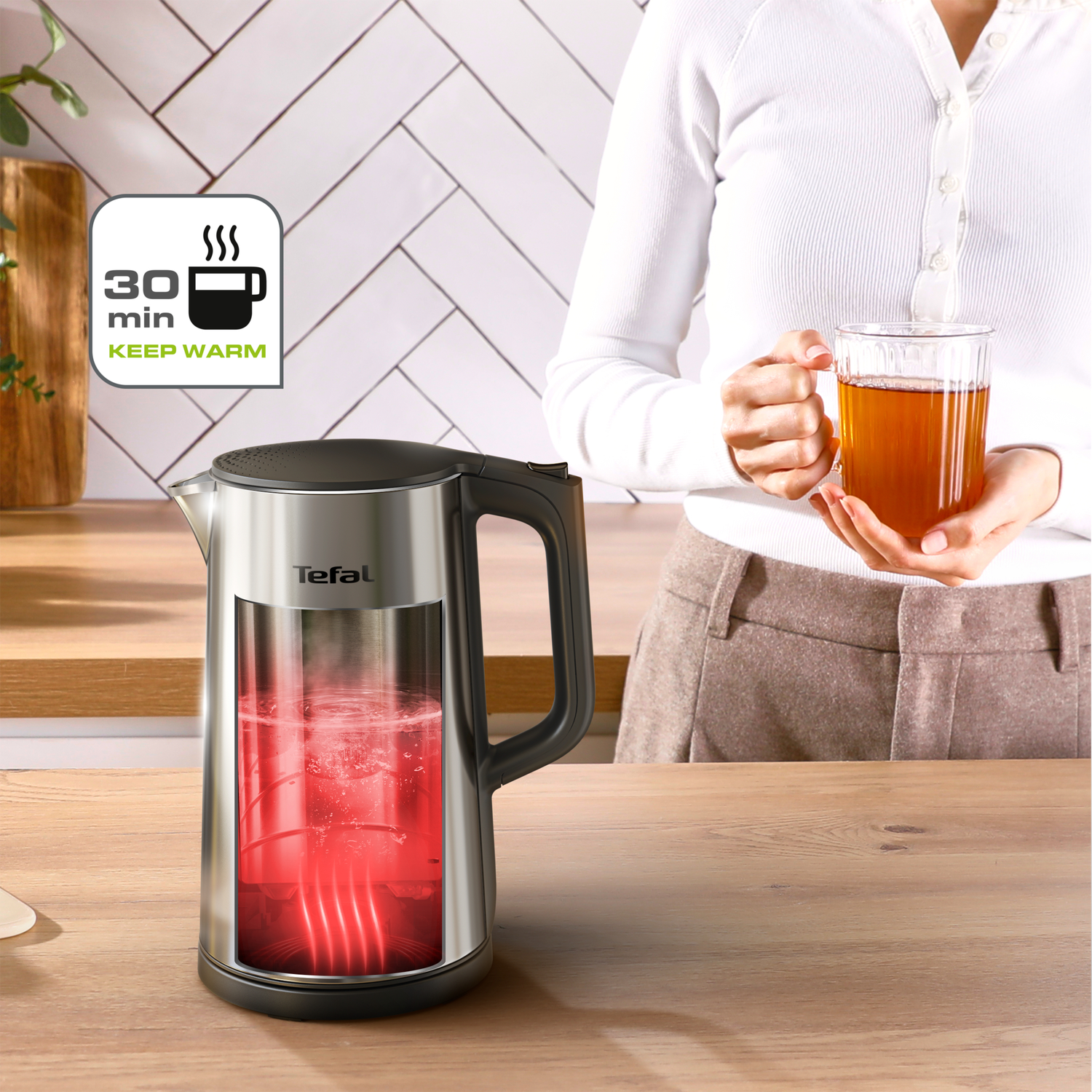 A woman holds tea near a kettle. The kettle is filled with red water. A "keep warm" icon is visible.