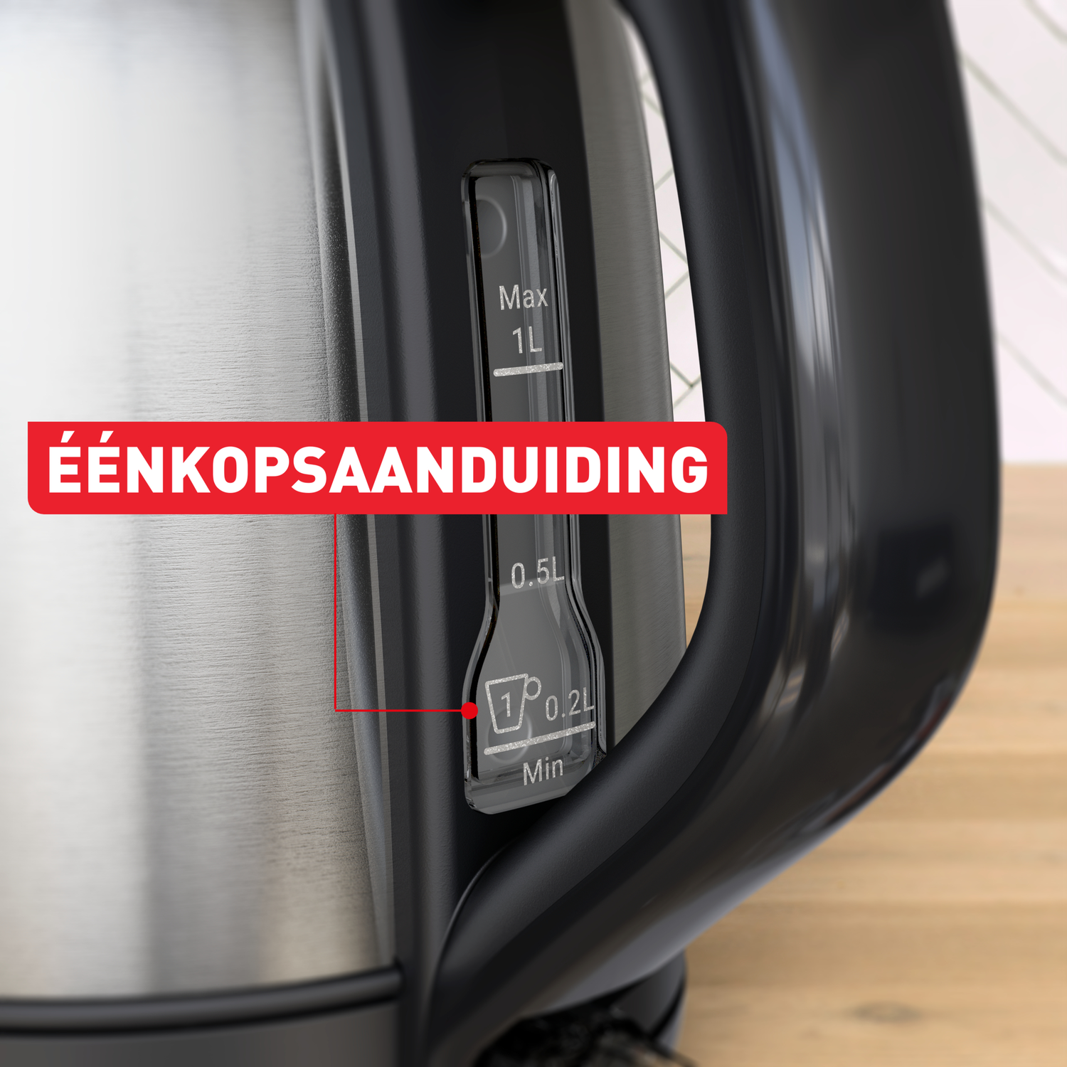 Close-up of a kettle. A red label says 'ÉÉNKOPSAANDUIDING.' A water level indicator shows measurements. The handle is black.