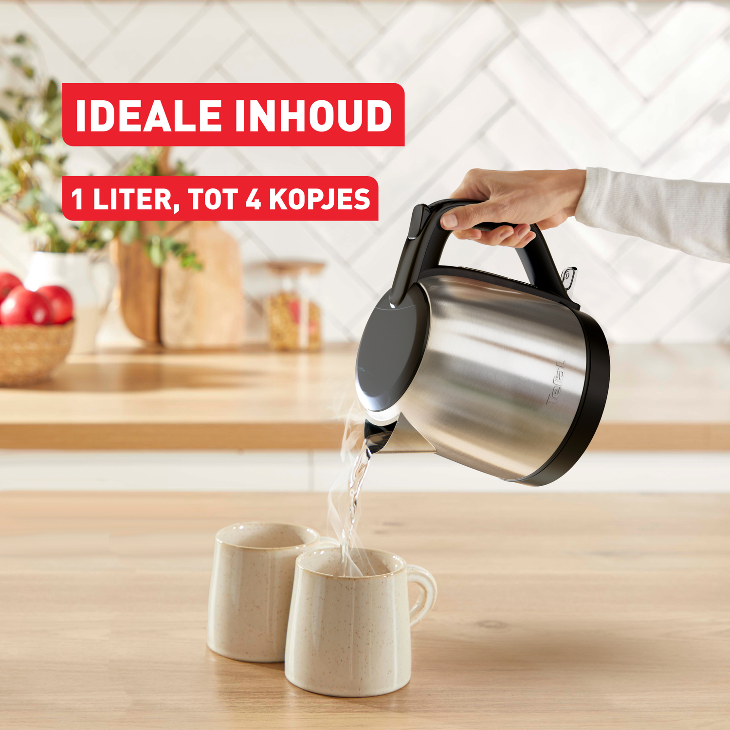 A person pours hot water from a silver kettle into two beige mugs on a wooden surface, kitchen background.