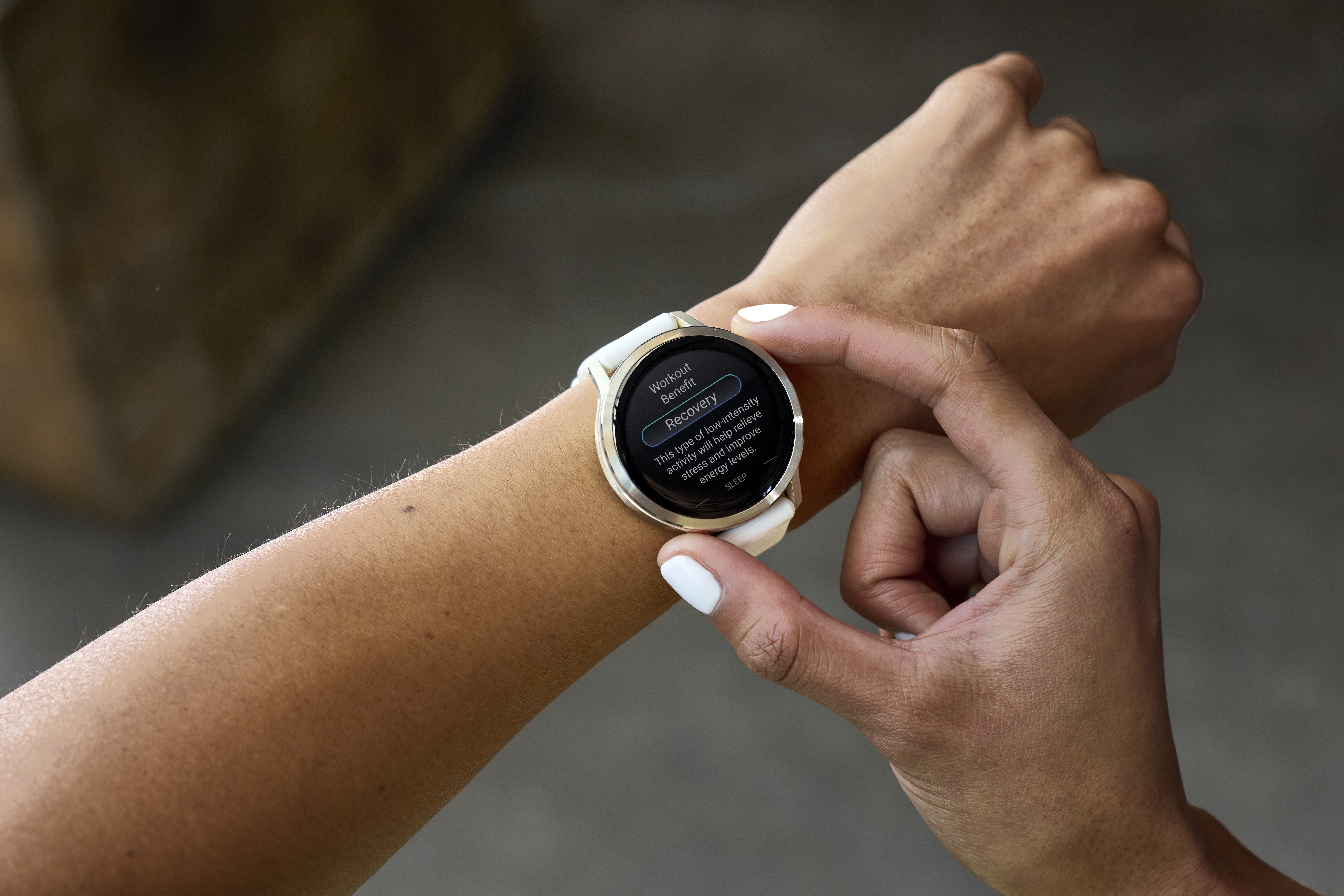 Arm einer Person mit Smartwatch, die 'Recovery' anzeigt. Der Finger der Person berührt das Ziffernblatt. Die Nägel sind weiß lackiert.