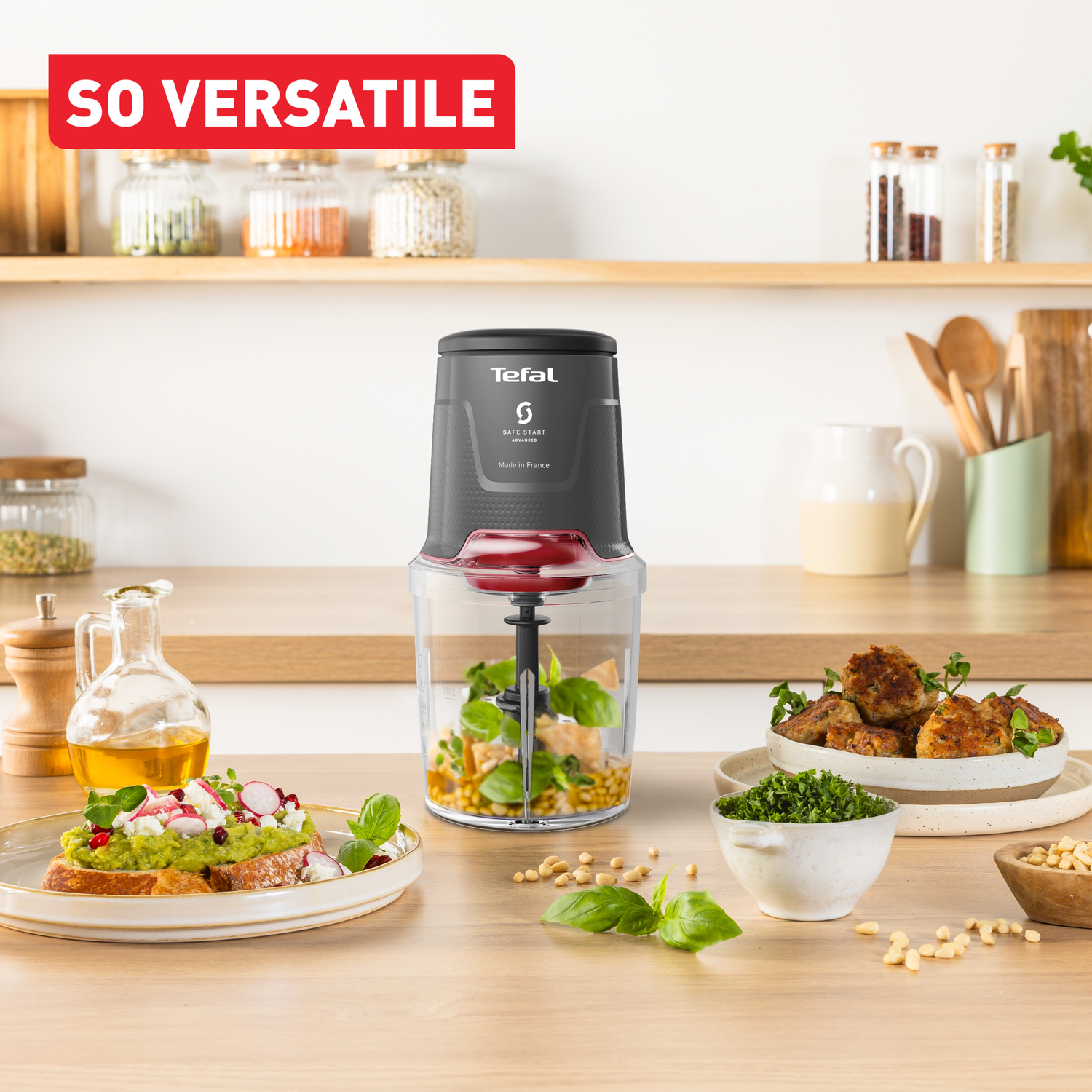 A food processor with ingredients and prepared dishes. Bread with guacamole, meatballs, and herbs on a wooden table.