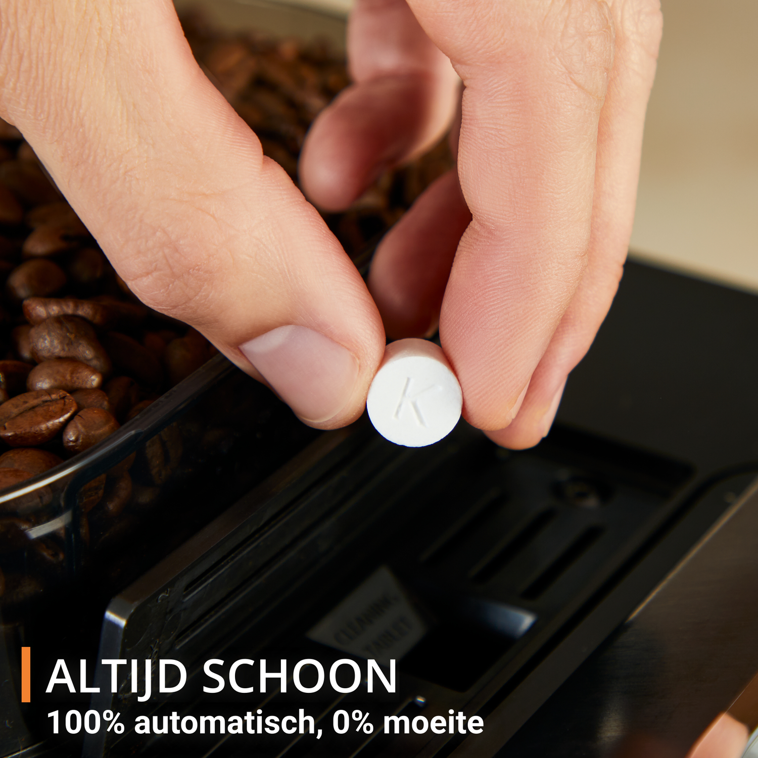 A hand holds a white tablet with a 'K' over a coffee machine's bean compartment. Coffee beans are visible. Text says 'Always clean'.