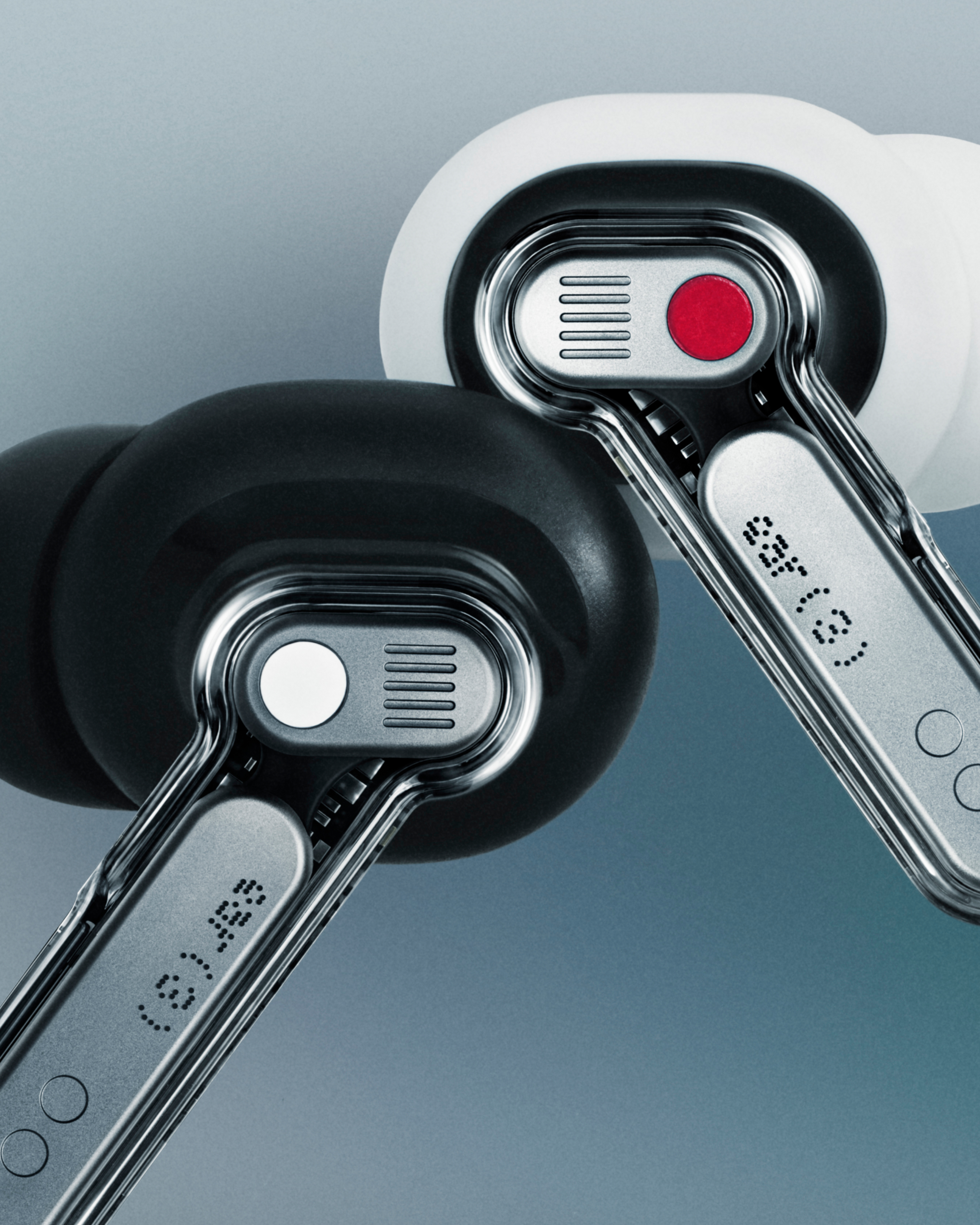 Nahaufnahme von zwei Ohrhörern. Einer schwarz, einer weiß. Beide silbern mit roten und weißen Akzenten. Blauer Hintergrund.