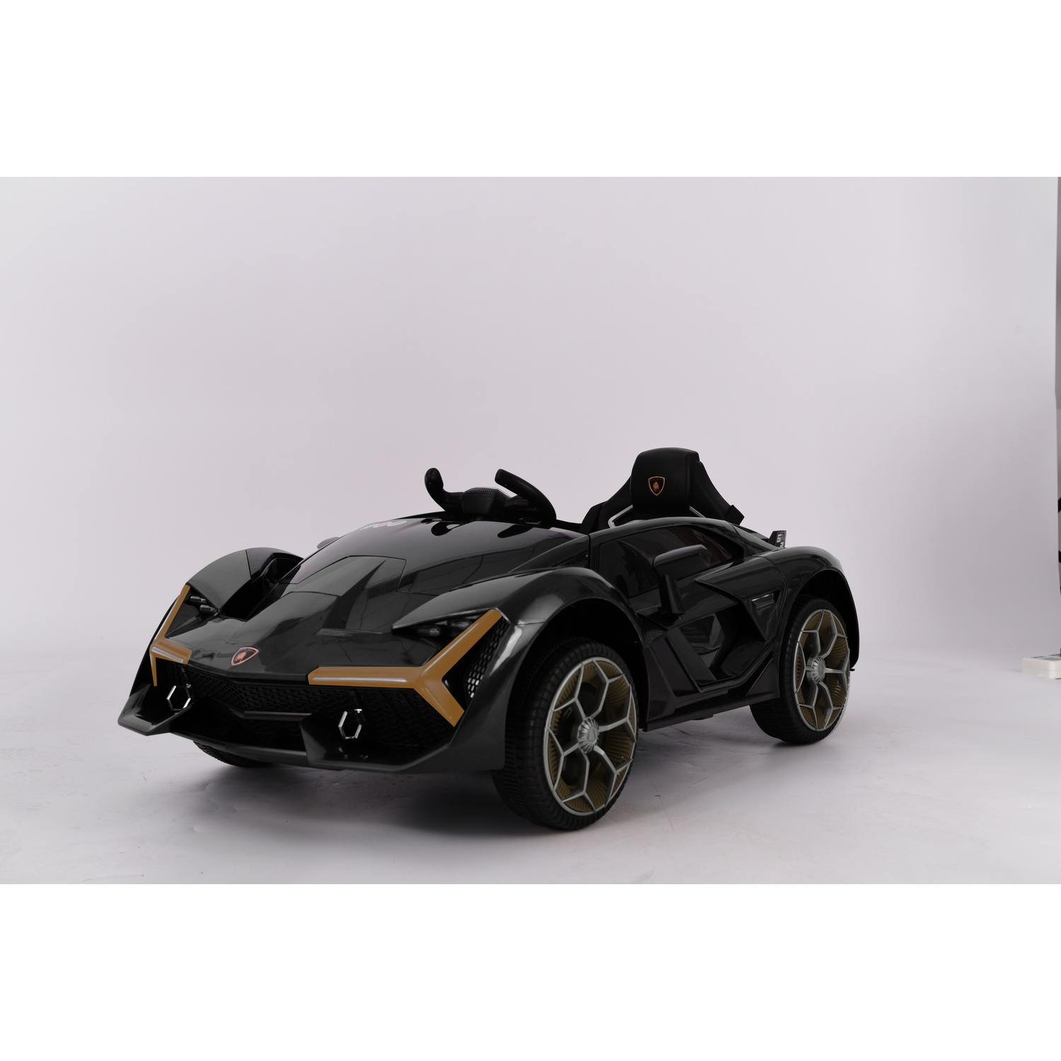 A black toy car, resembling a Lamborghini, is centered on a white background. It has gold accents and a black interior.