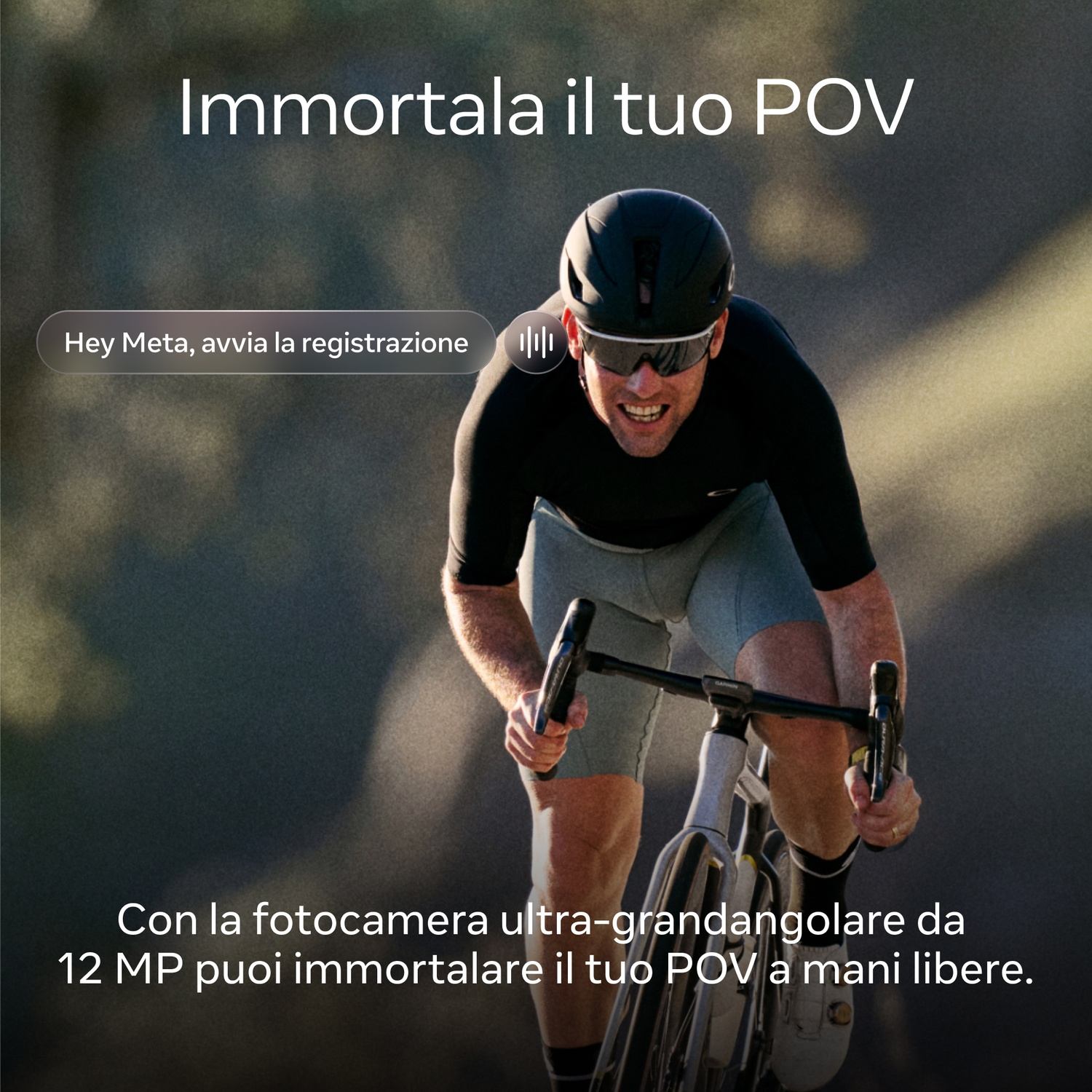 Ciclista in bicicletta. Indossa casco e occhiali da sole. Lo sfondo è sfocato.
