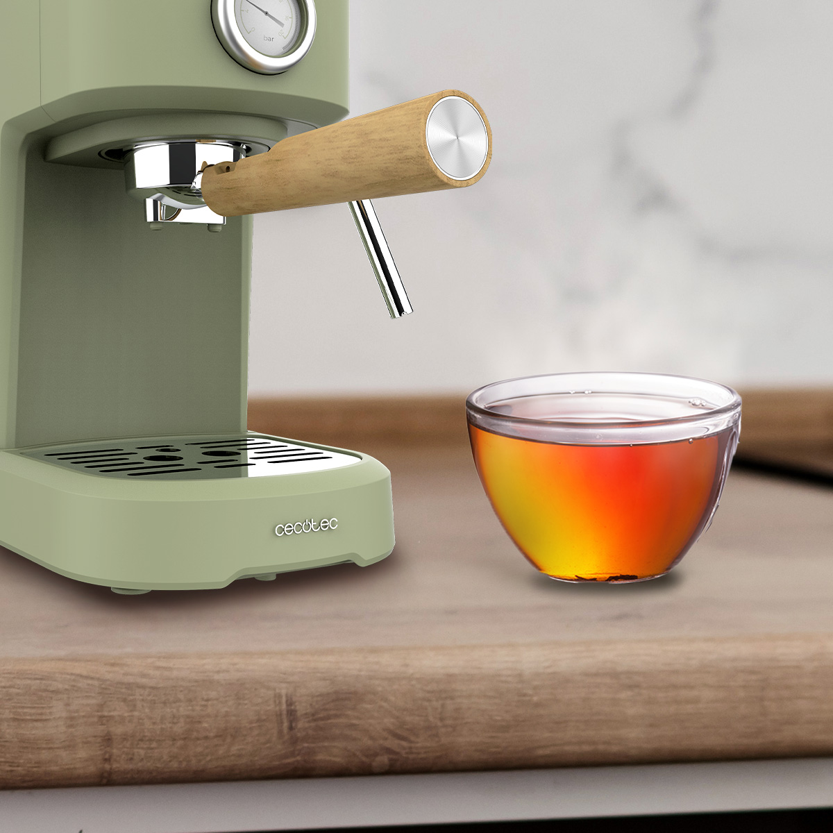 Una máquina de espresso verde con un mango de madera y una taza de té en una superficie de madera.