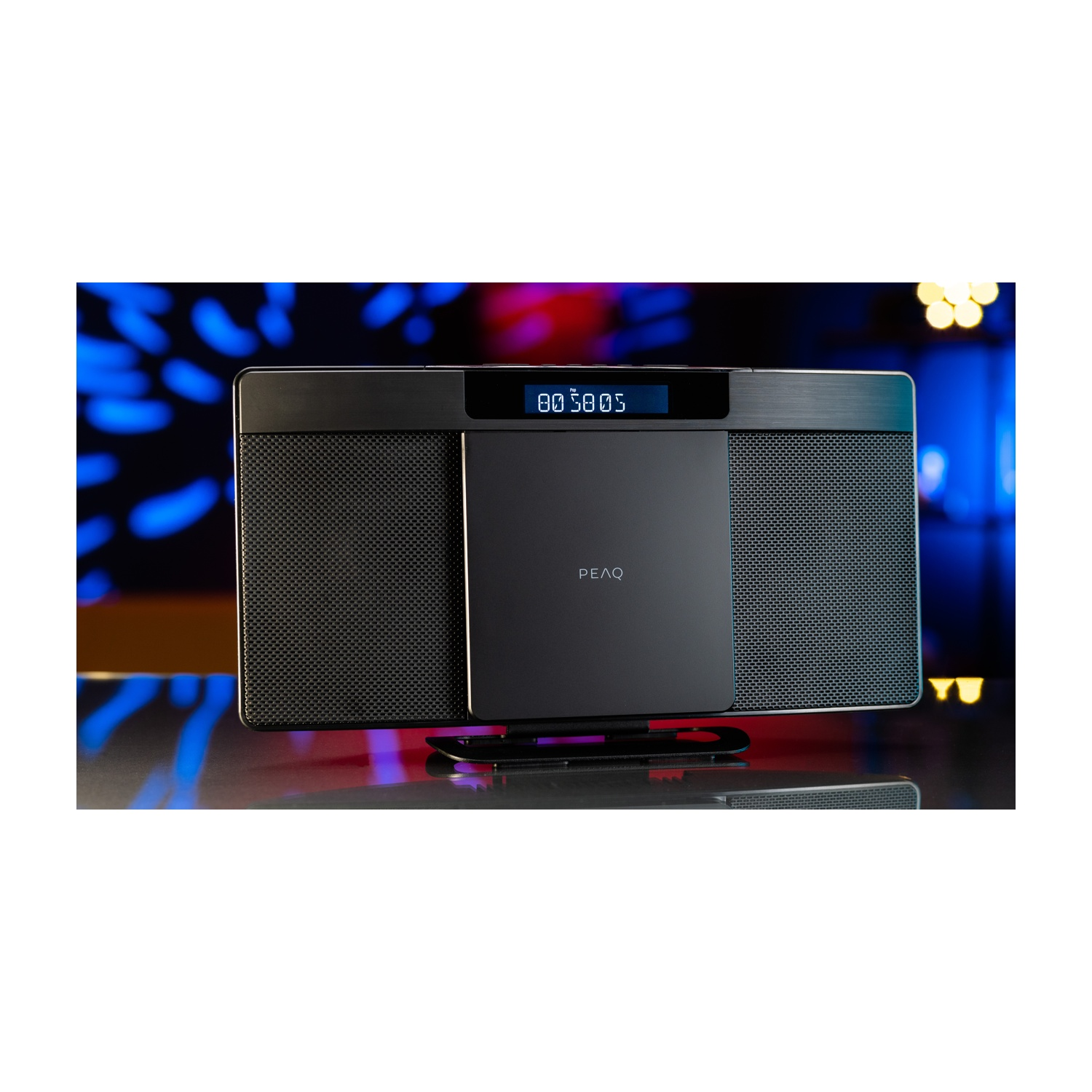 Un impianto stereo nero e argento su una superficie riflettente. Ha un display con numeri e il marchio PEAQ.